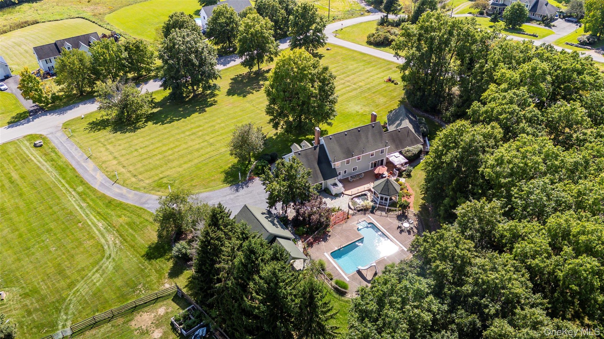 Beautiful corner lot with private inground swimming pool surrounding patio, gazebo, expansive green space, and mature trees