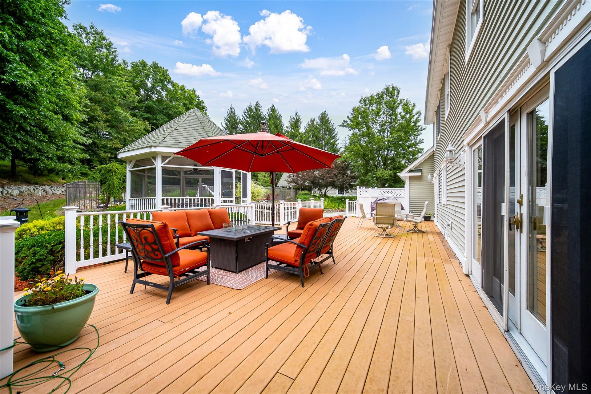 Expansive outdoor deck with a screened gazebo,  and dual sliding glass doors to kitchen area.