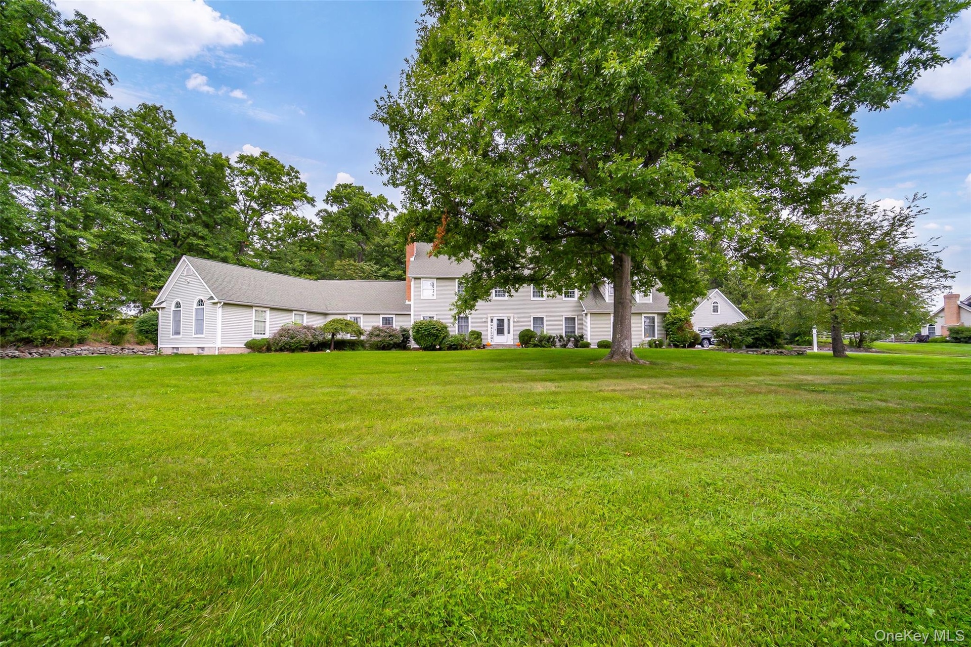 Expansive green lawn with mature trees.