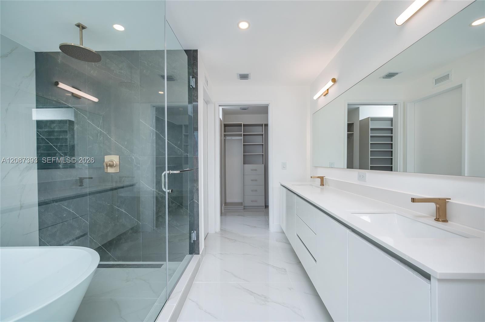 Elegant bathroom with lighted mirrors and lamps matching the brass fixtures