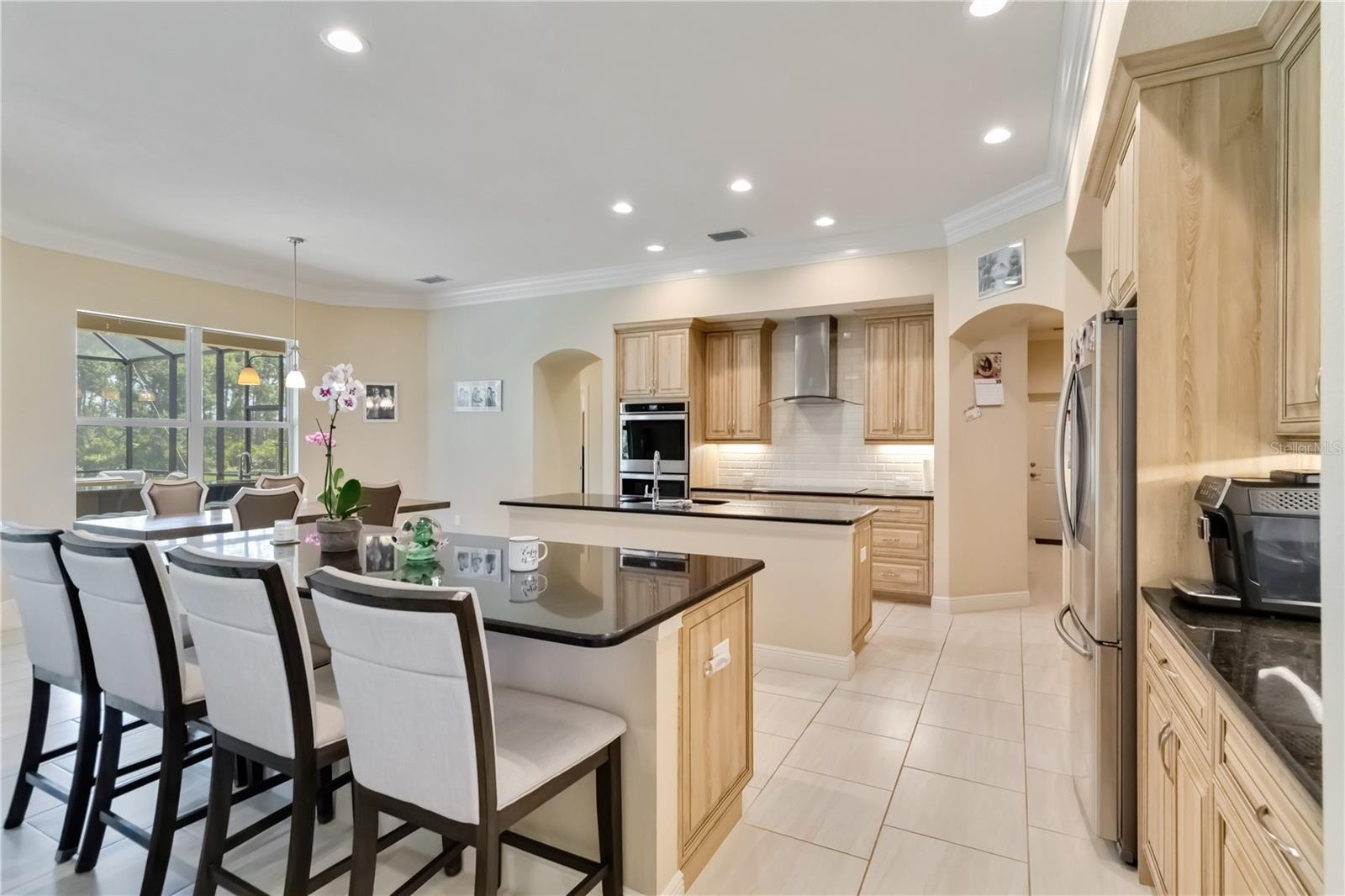 Large kitchen with double ovens, stainless steel appliances, granite counters and two islands. One island serves as an eating bar. The other island is