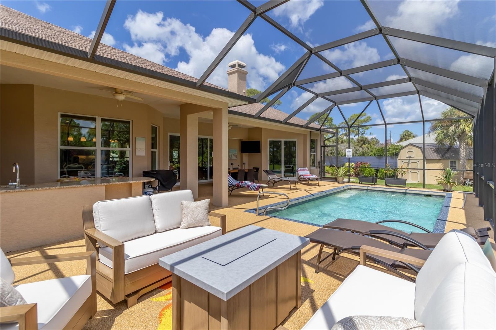 The covered area has two ceiling fans and can lights. Notice the TV (swim and watch your favorite shows at the same time!) and the outdoor kitchen. Th