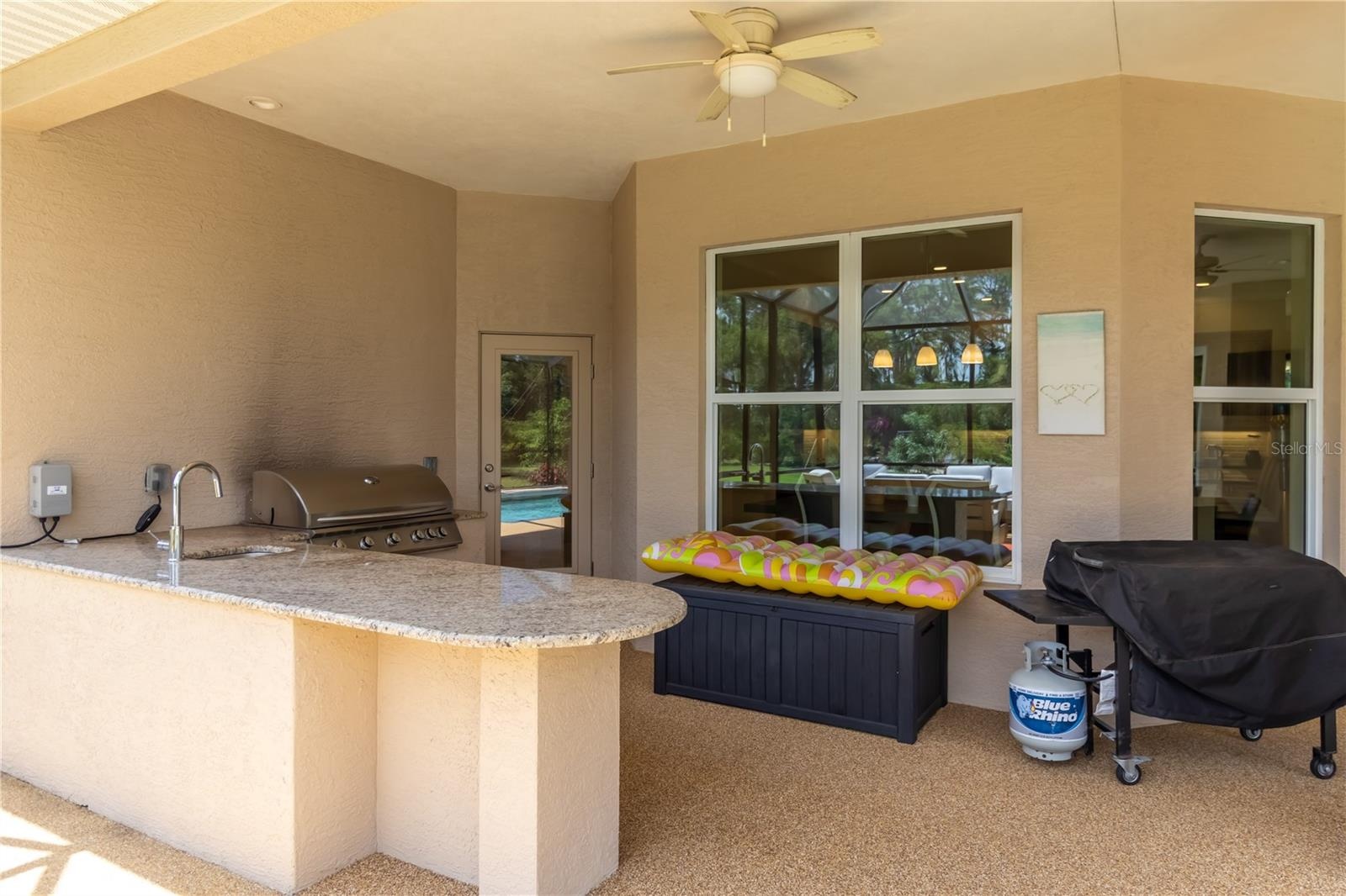 The outdoor kitchen has a built-in grill, sink, and fridge.