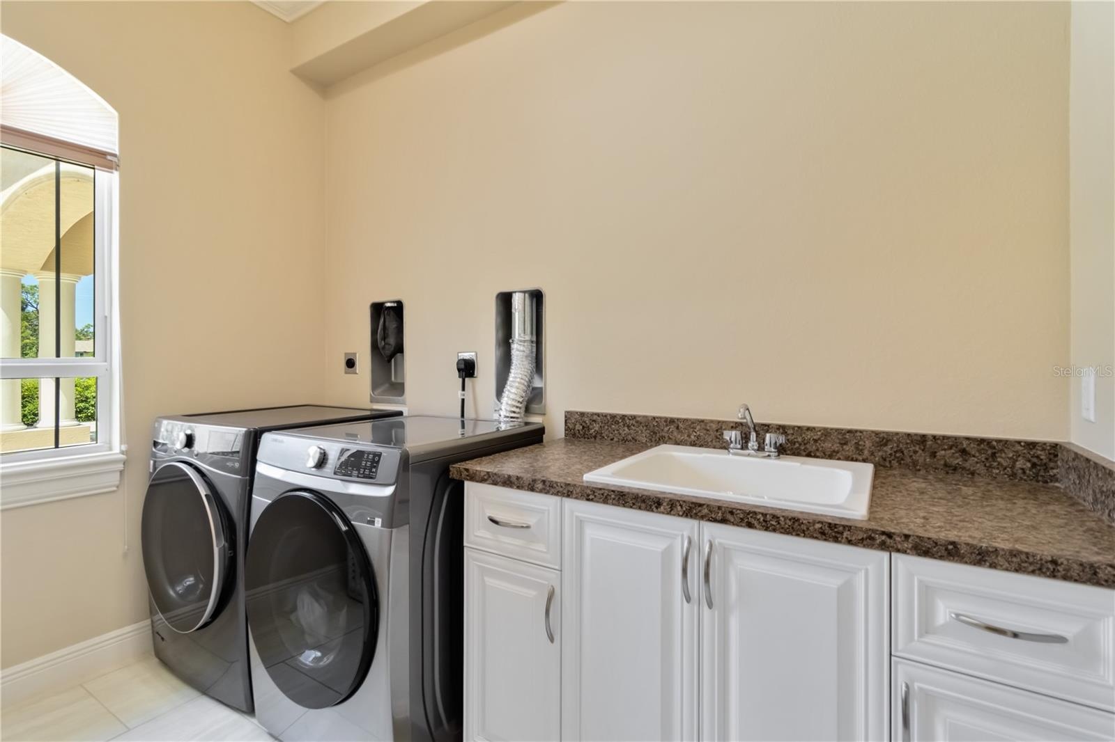 The Landry room offers storage shelving on the wall not shown in this picture.  Notice the two outlets and dryer vents. This laundry room was designed
