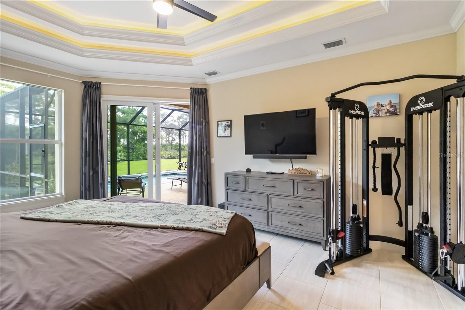 Primary bedroom. Notice the natural light and the slider leading to the pool. Also, notice the tray ceiling.