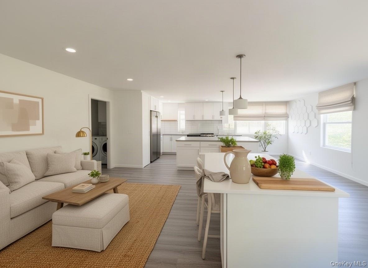 Virtually staged. Open-concept living room and kitchen with center island, pendant lighting and multiple windows.