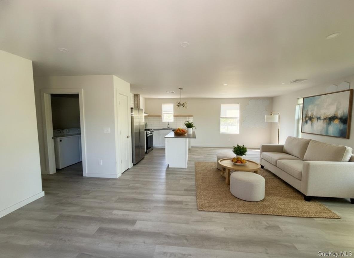 Virtually staged. Open floor plan living area with view to the kitchen island and stainless appliances.