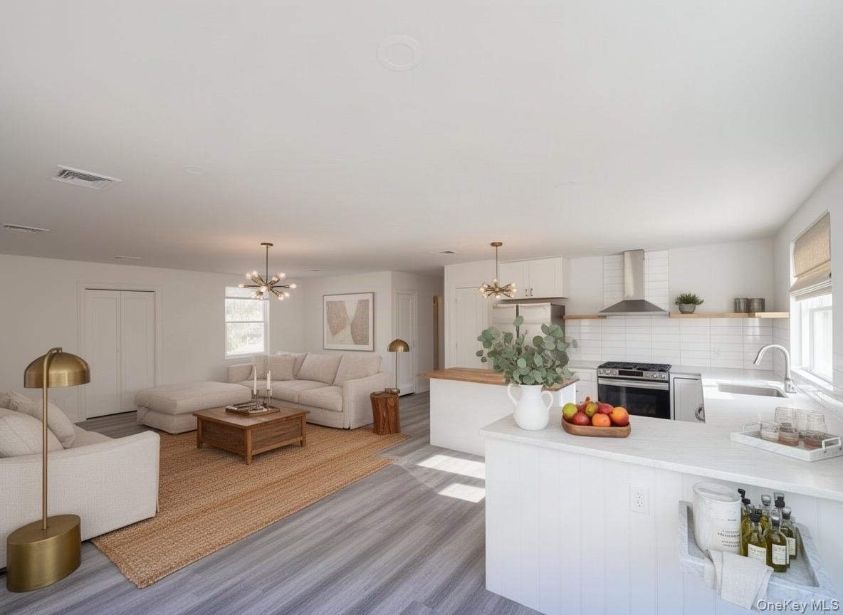Virtually staged. Wide view of the open living space and kitchen with island and range hood.
