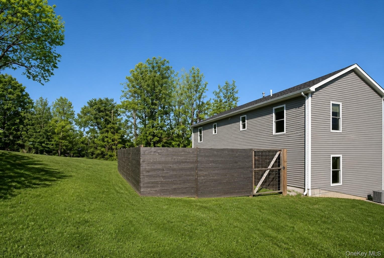 Side elevation with the fenced yard area and open lawn.