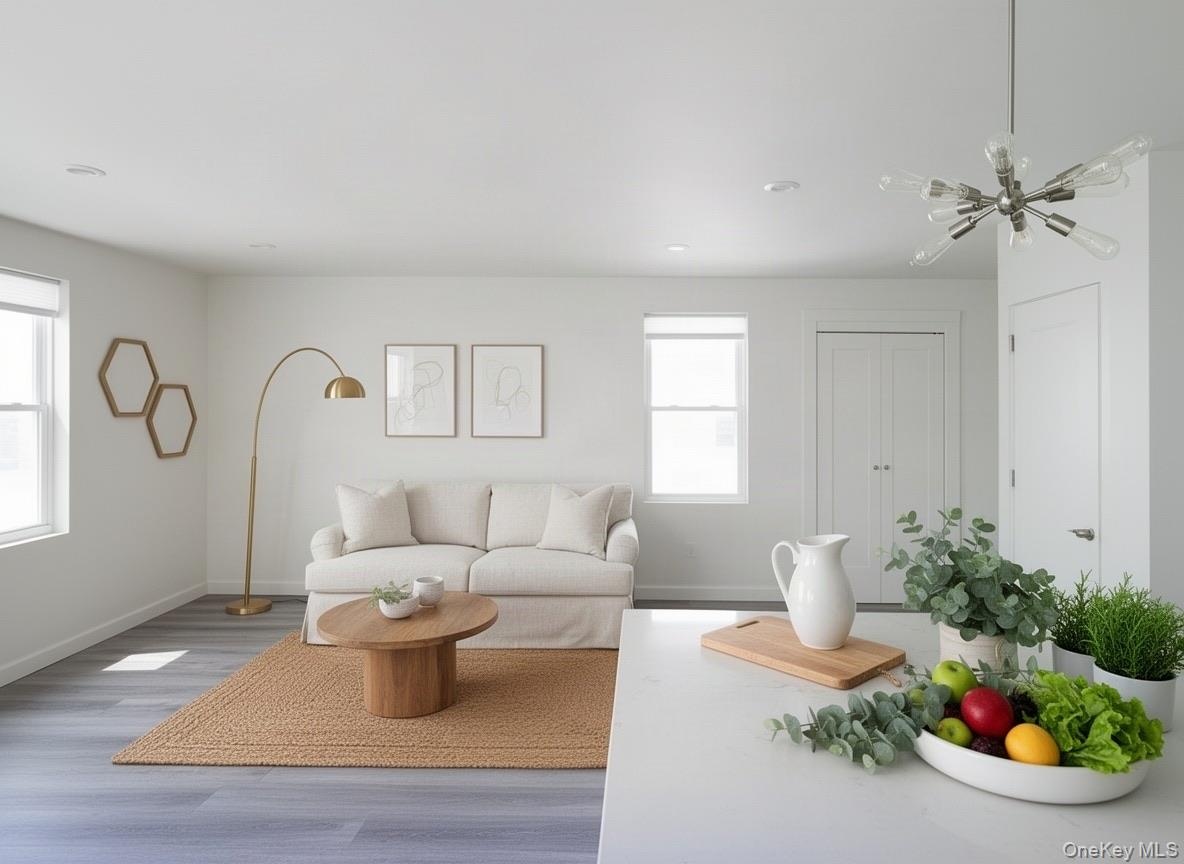 Virtually staged. Living area off the kitchen with windows and wood-look plank flooring.
