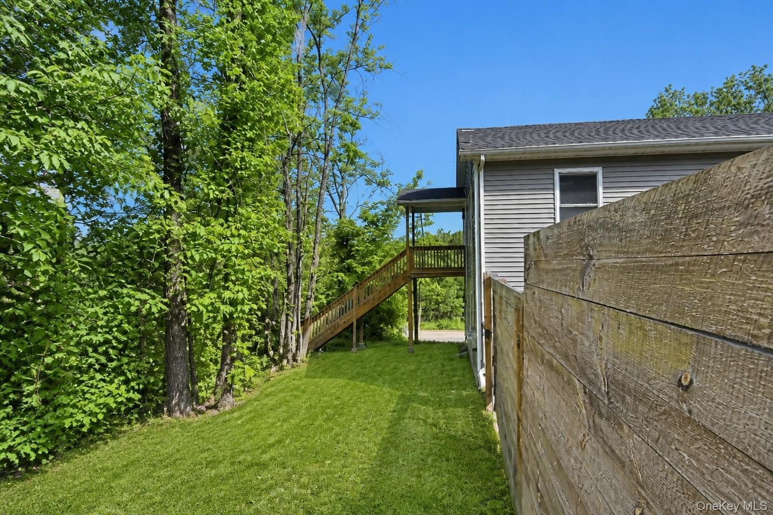 Side yard along the wood privacy fence with mature trees and the home beyond.