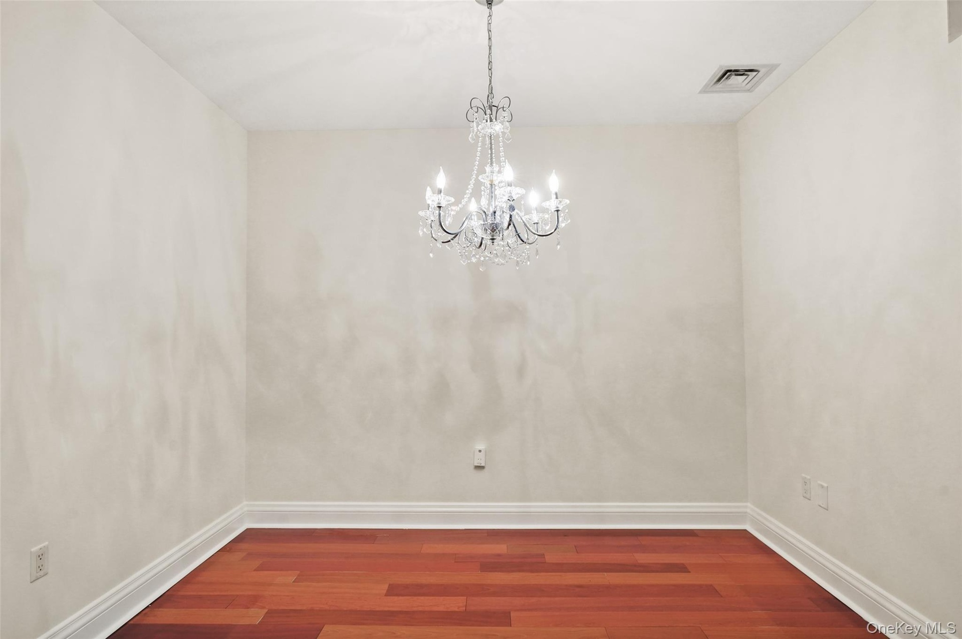 Wood-finish flooring, crown molding, and a crystal chandelier
