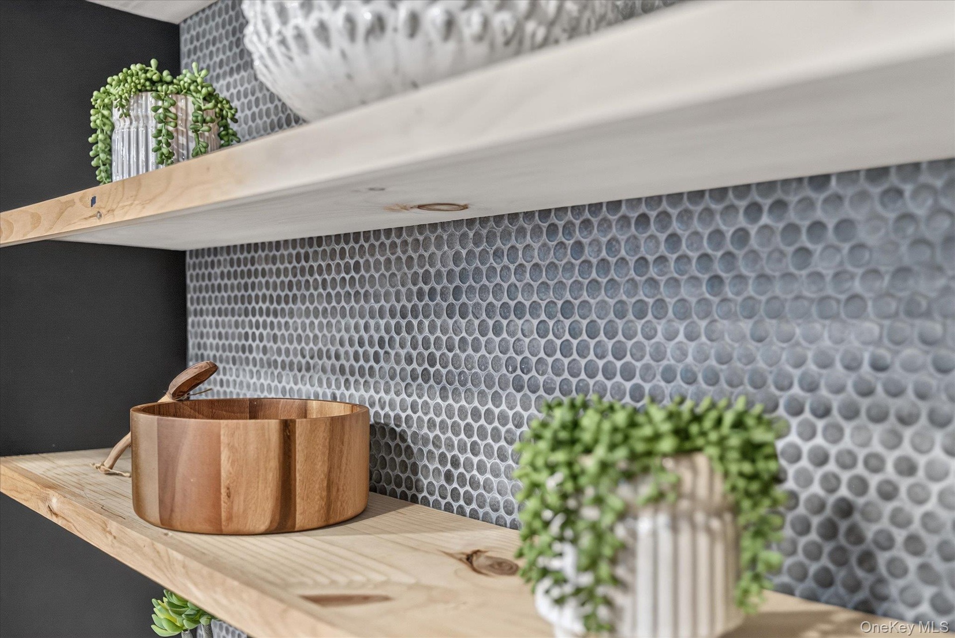 Floating wood shelving against a penny tile backsplash