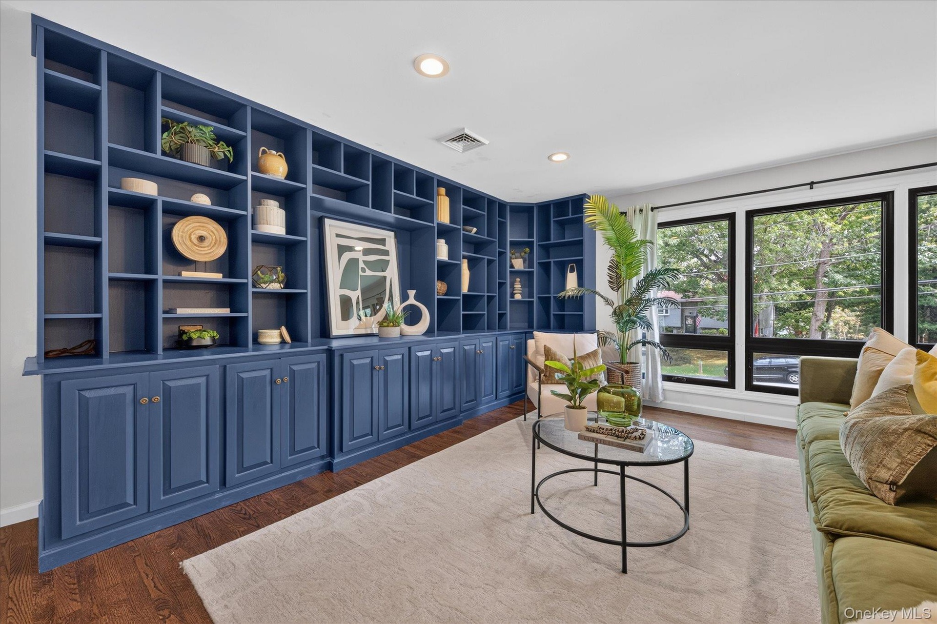 Built-in shelving with lower cabinetry, wood-finish flooring, recessed lighting, and large windows with dark frames