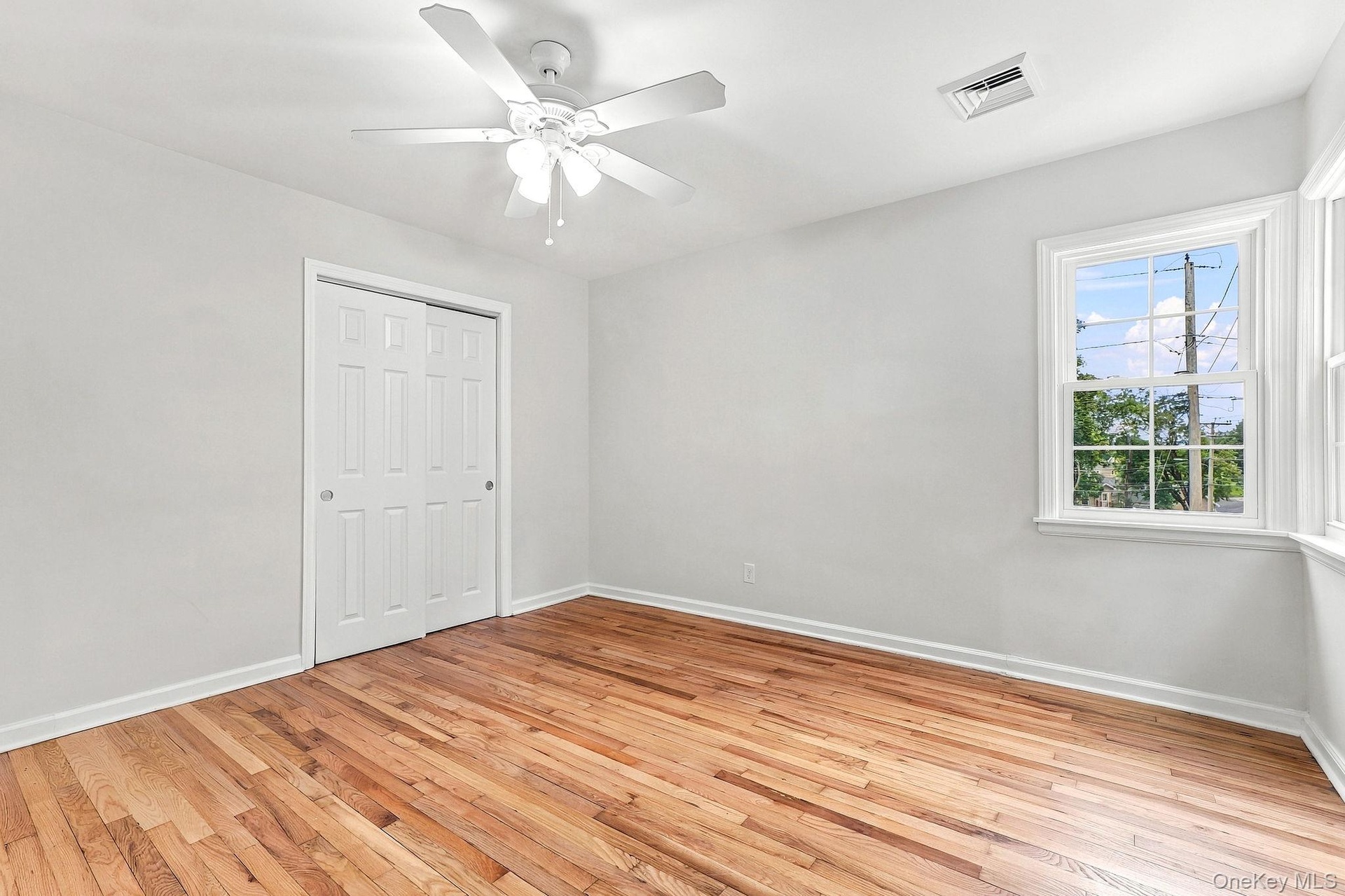 Wood-finish flooring, white walls, and a ceiling fan with integrated lighting