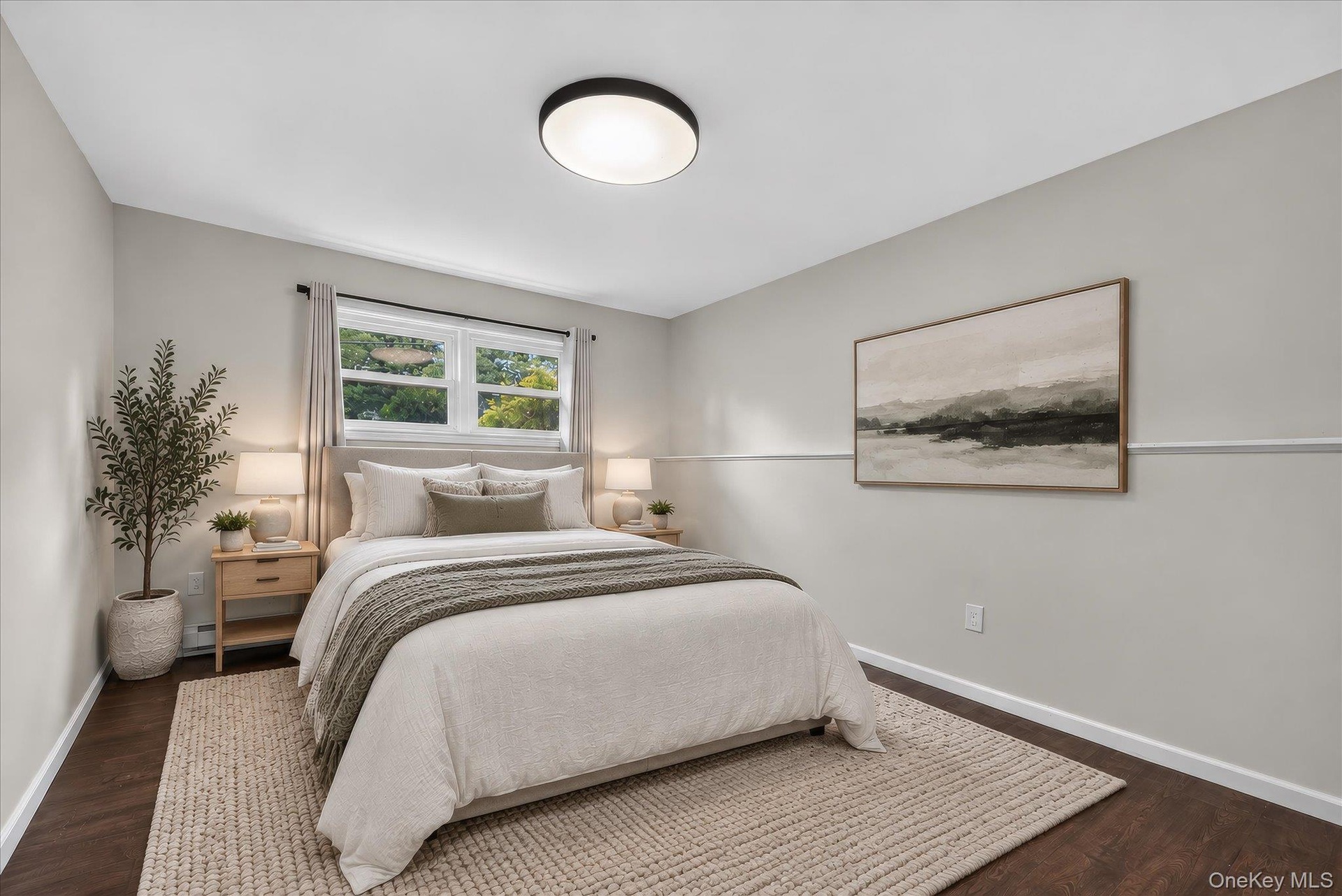 Lower level bedroom--Wood-finish flooring, white trim details, window with natural light, modern flush-mount ceiling light, and light-toned walls