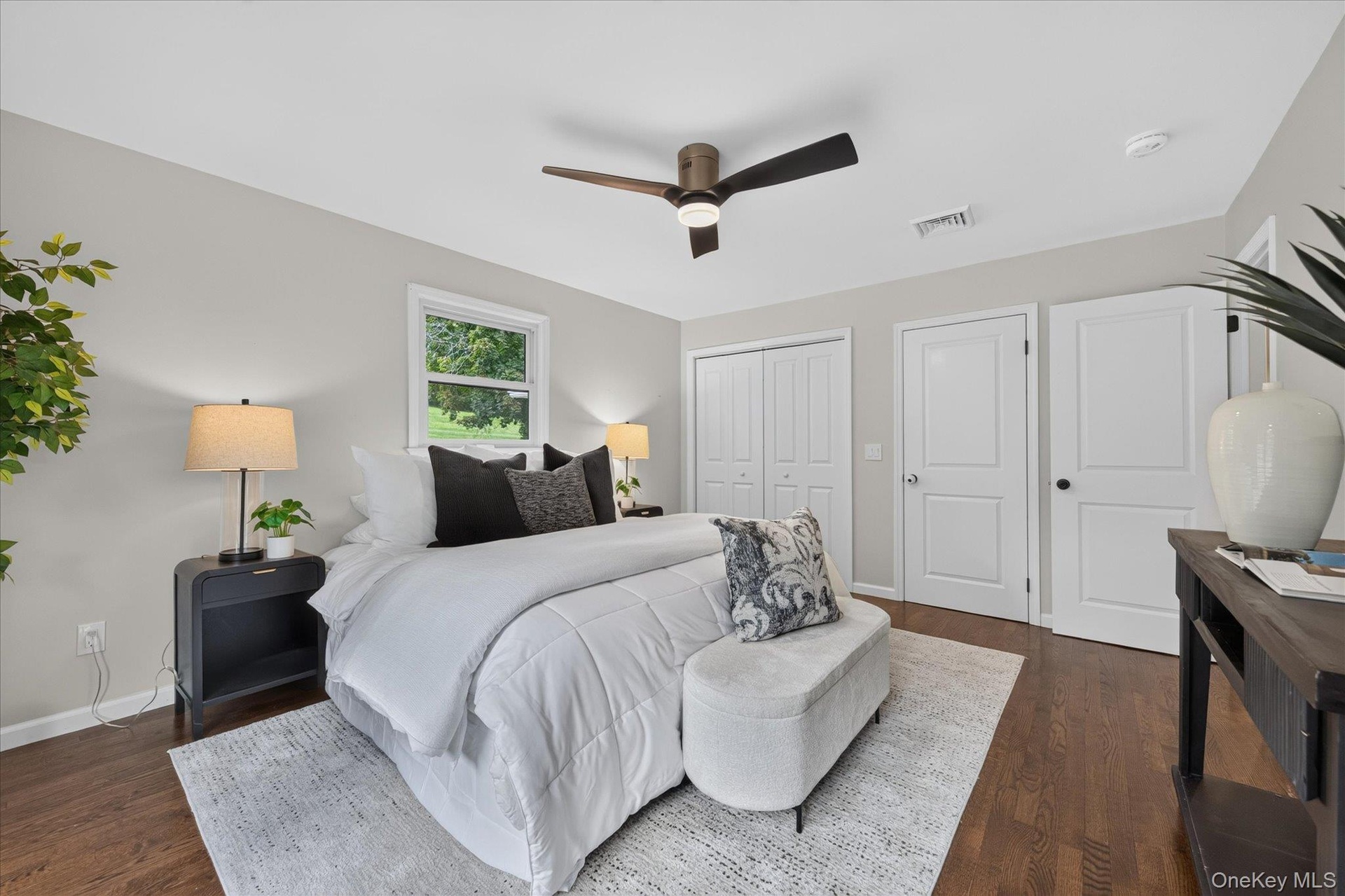 Hardwood-style flooring, white walls, two white panel doors, and a ceiling fan with light fixture