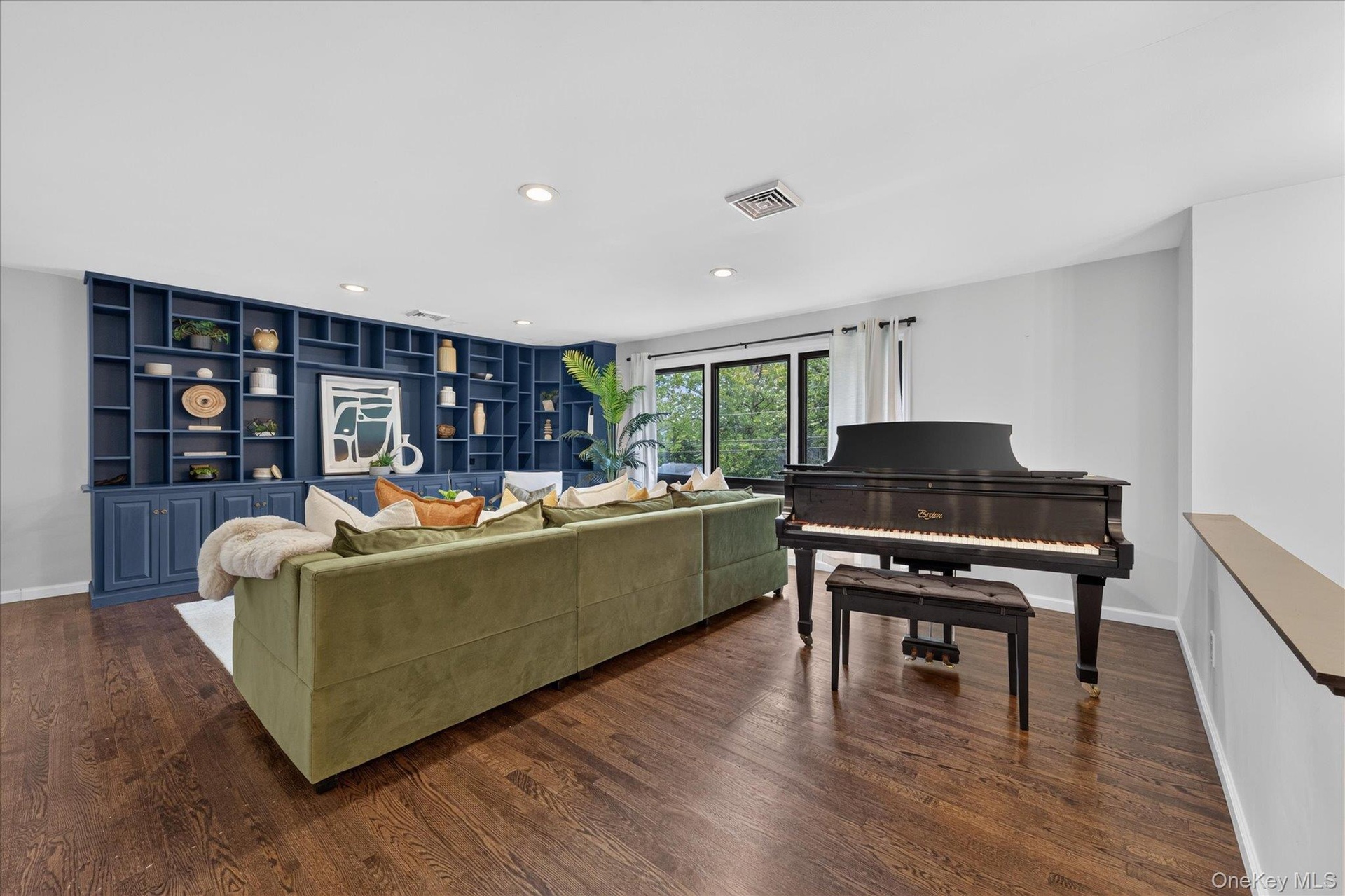 Hardwood flooring, custom built-in shelving, recessed lighting, and large windows with dark trim