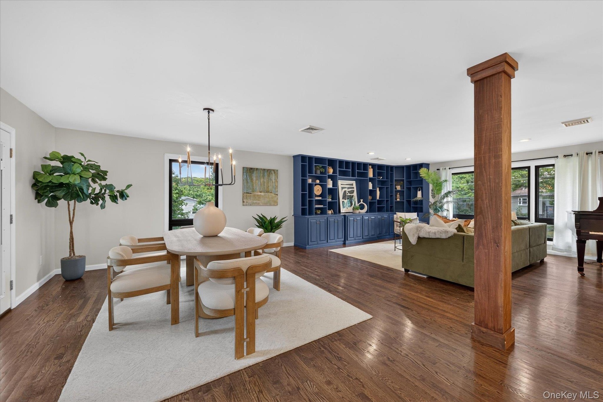 Loft-like, Open Floor plan--Hardwood flooring throughout, built-in shelving, large windows with exterior foliage, and a rectangular chandelier