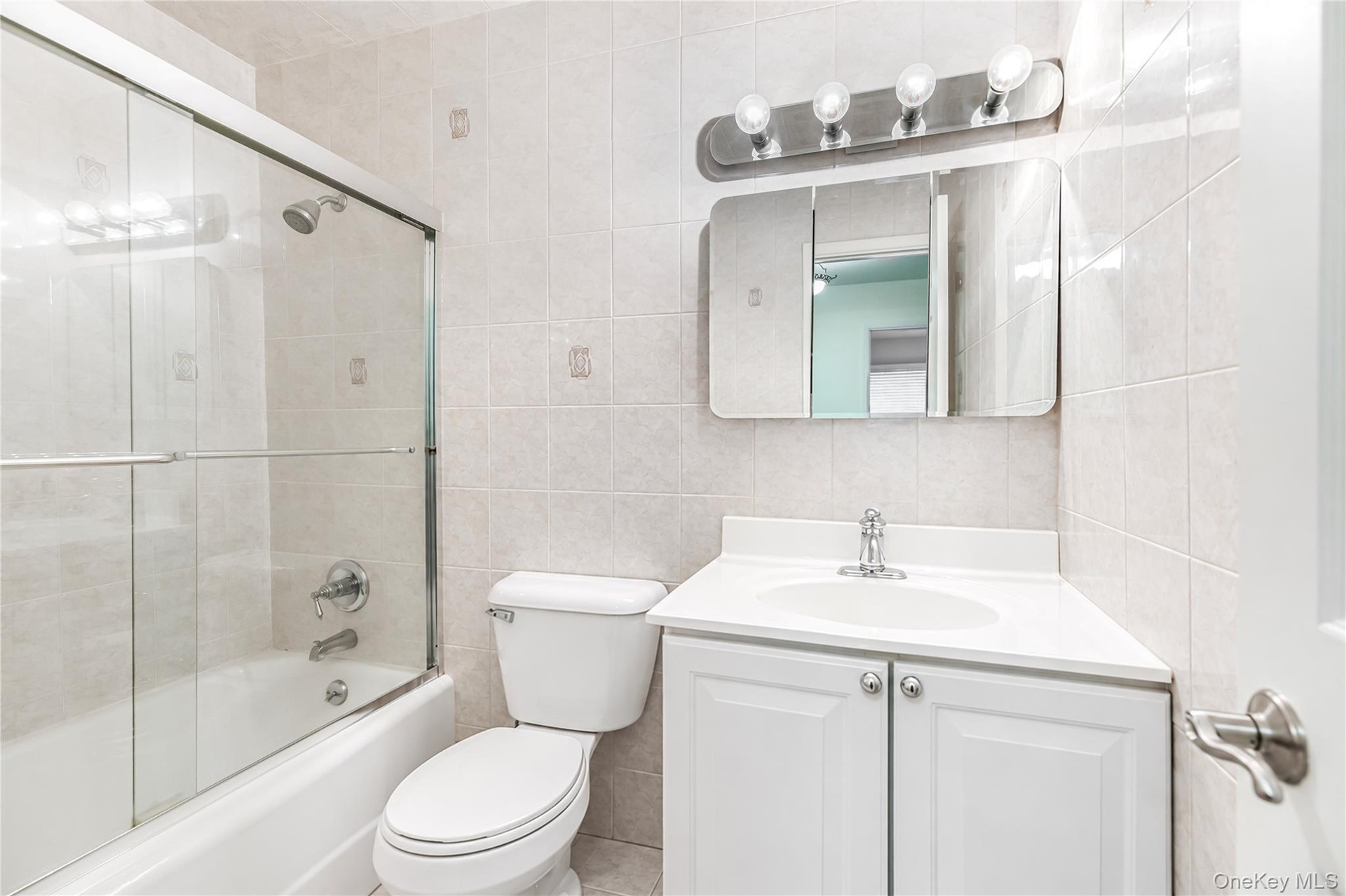 Bathroom featuring a white vanity with integrated sink, chrome faucet, and a medicine cabinet with a vanity light fixture
