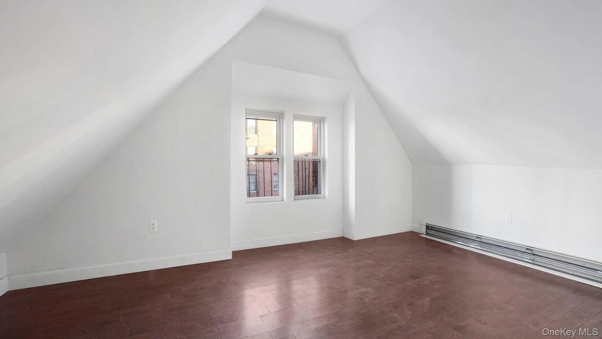 Bonus room featuring a baseboard heating unit, dark wood-type flooring, and vaulted ceiling