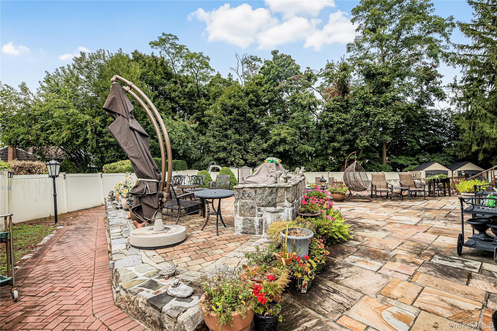 Expansive patio featuring flagstone paving, a stone-faced retaining wall, and a brick pathway