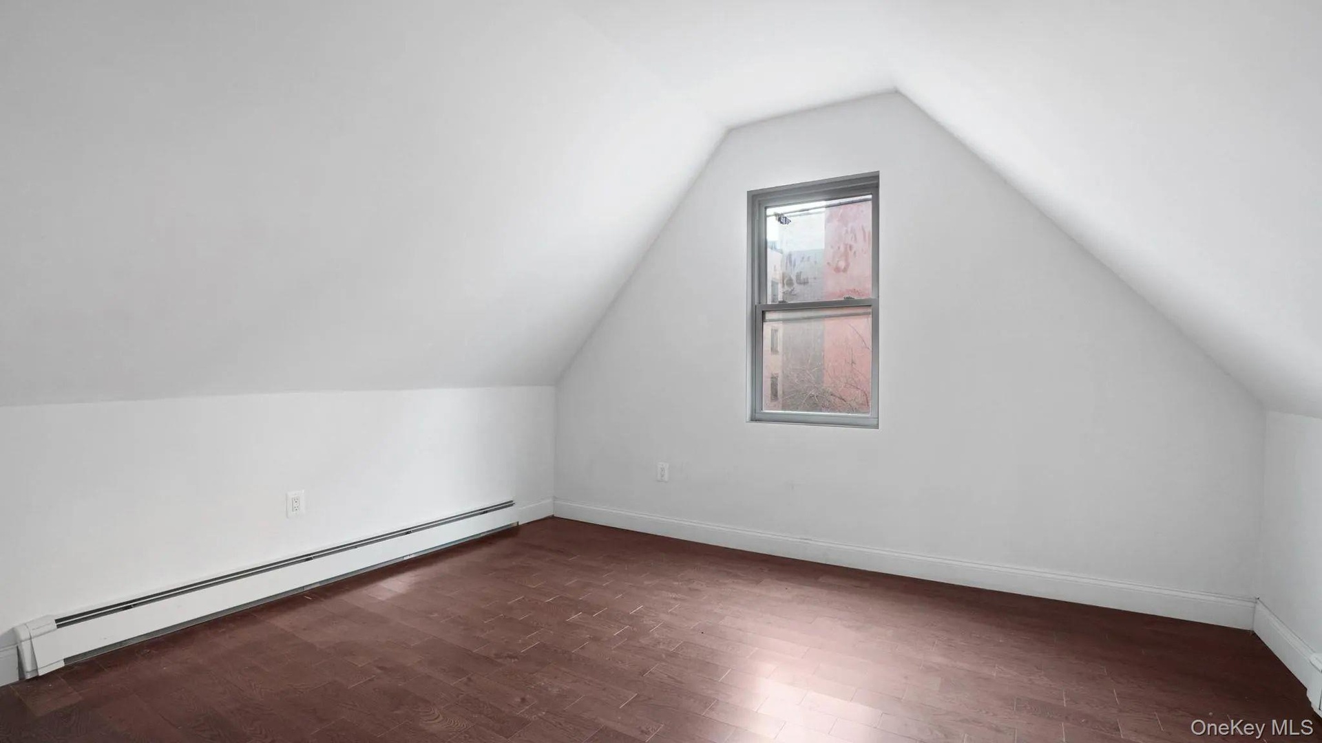 Additional living space with dark hardwood / wood-style flooring, a baseboard heating unit, and vaulted ceiling