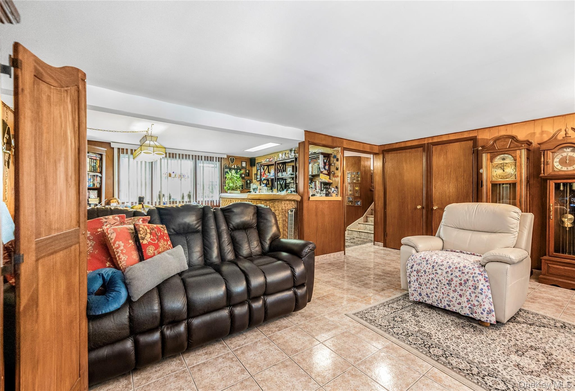 Tiled flooring, wood paneling, built-in media cabinetry, and a pass-through opening