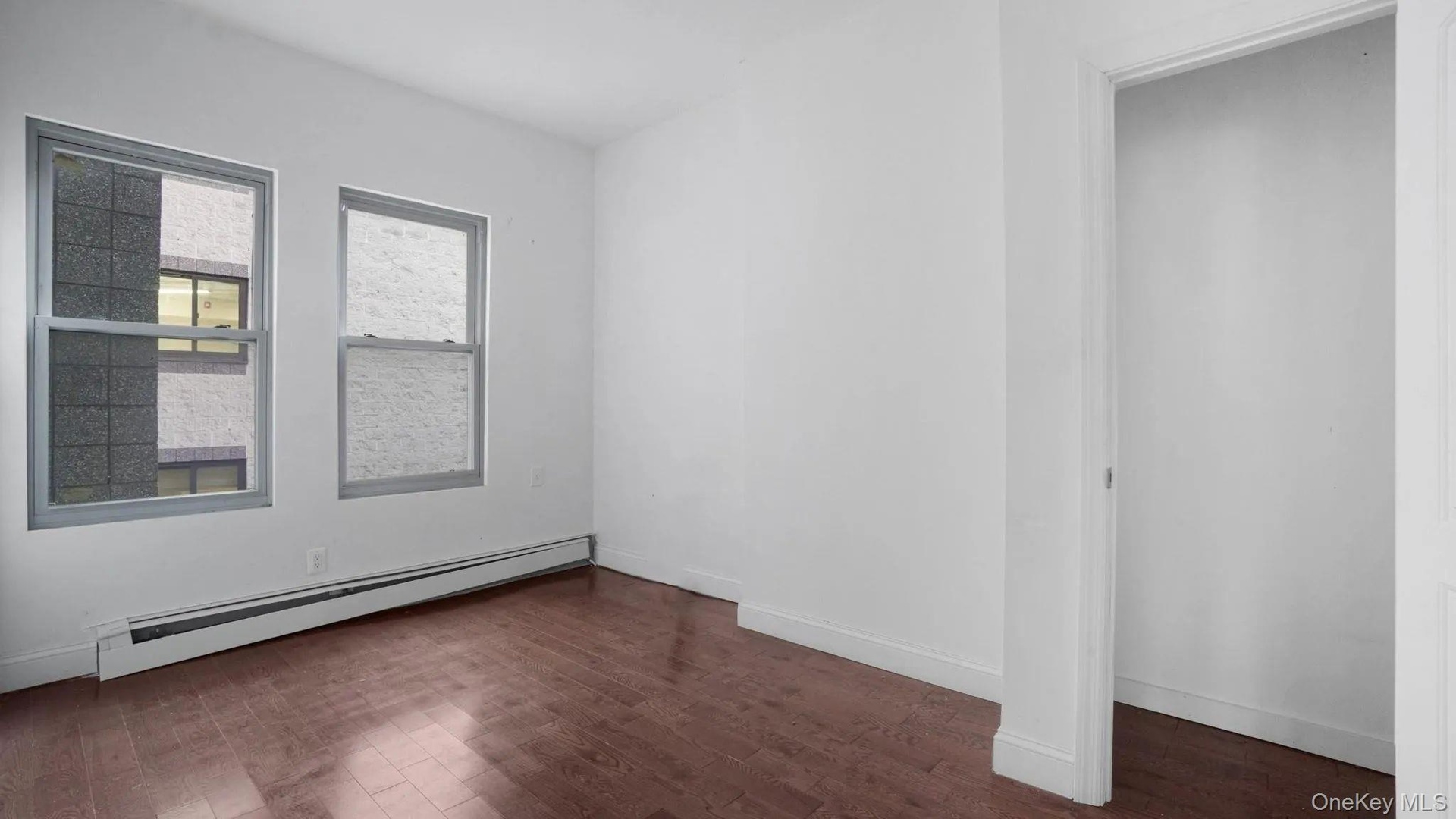 Empty room featuring baseboard heating and dark wood-type flooring