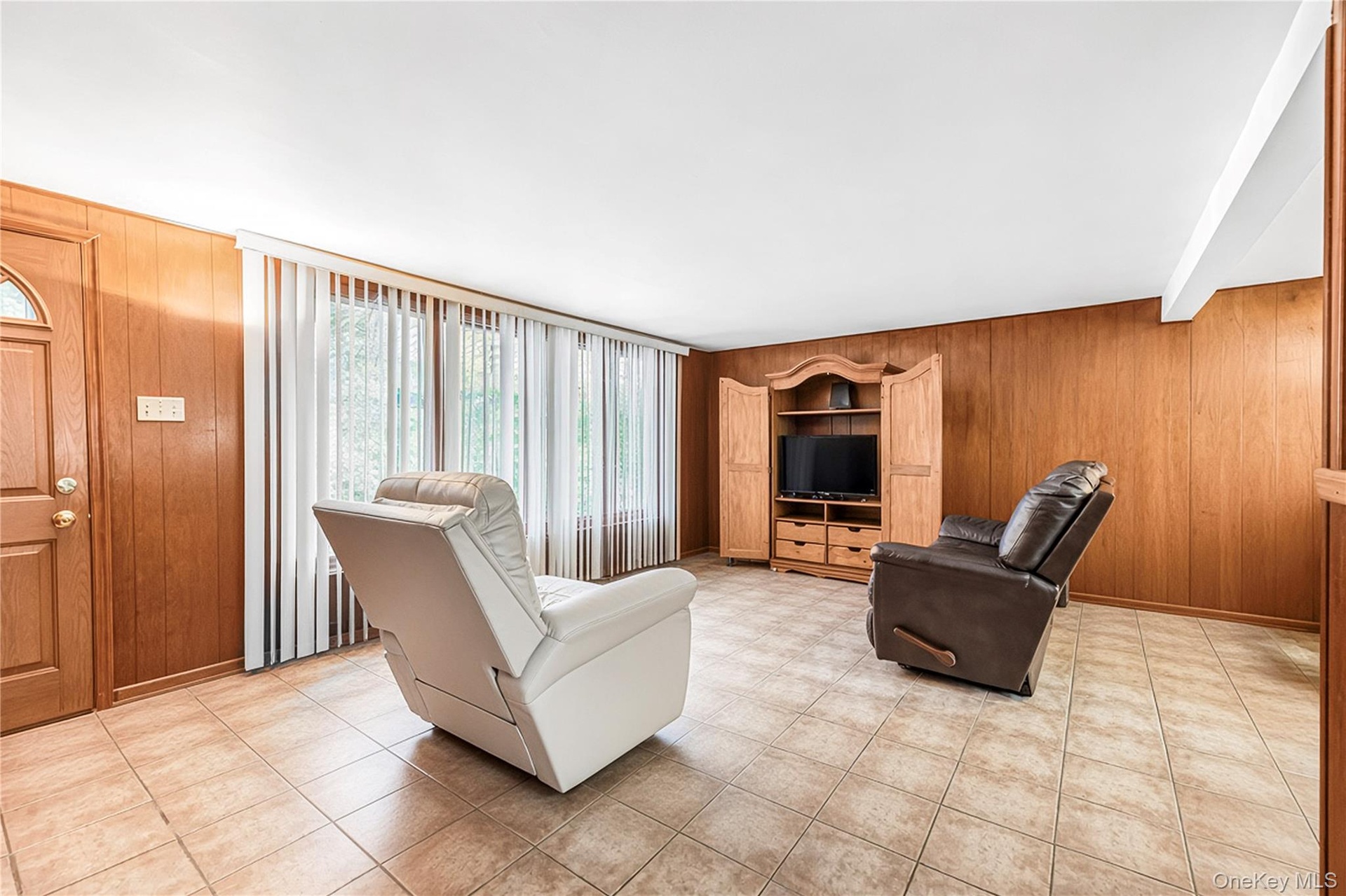 Tiled flooring, wood paneling, built-in media cabinetry, and a pass-through opening