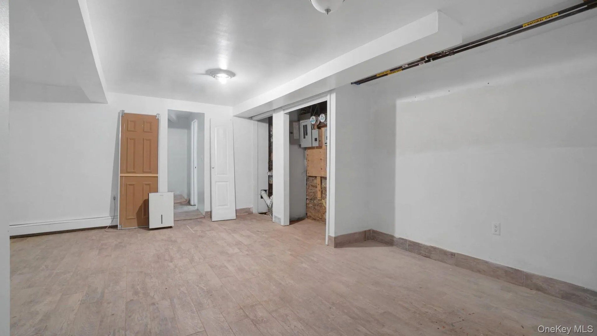 Unfurnished bedroom featuring a baseboard radiator, connected bathroom, and light wood-type flooring