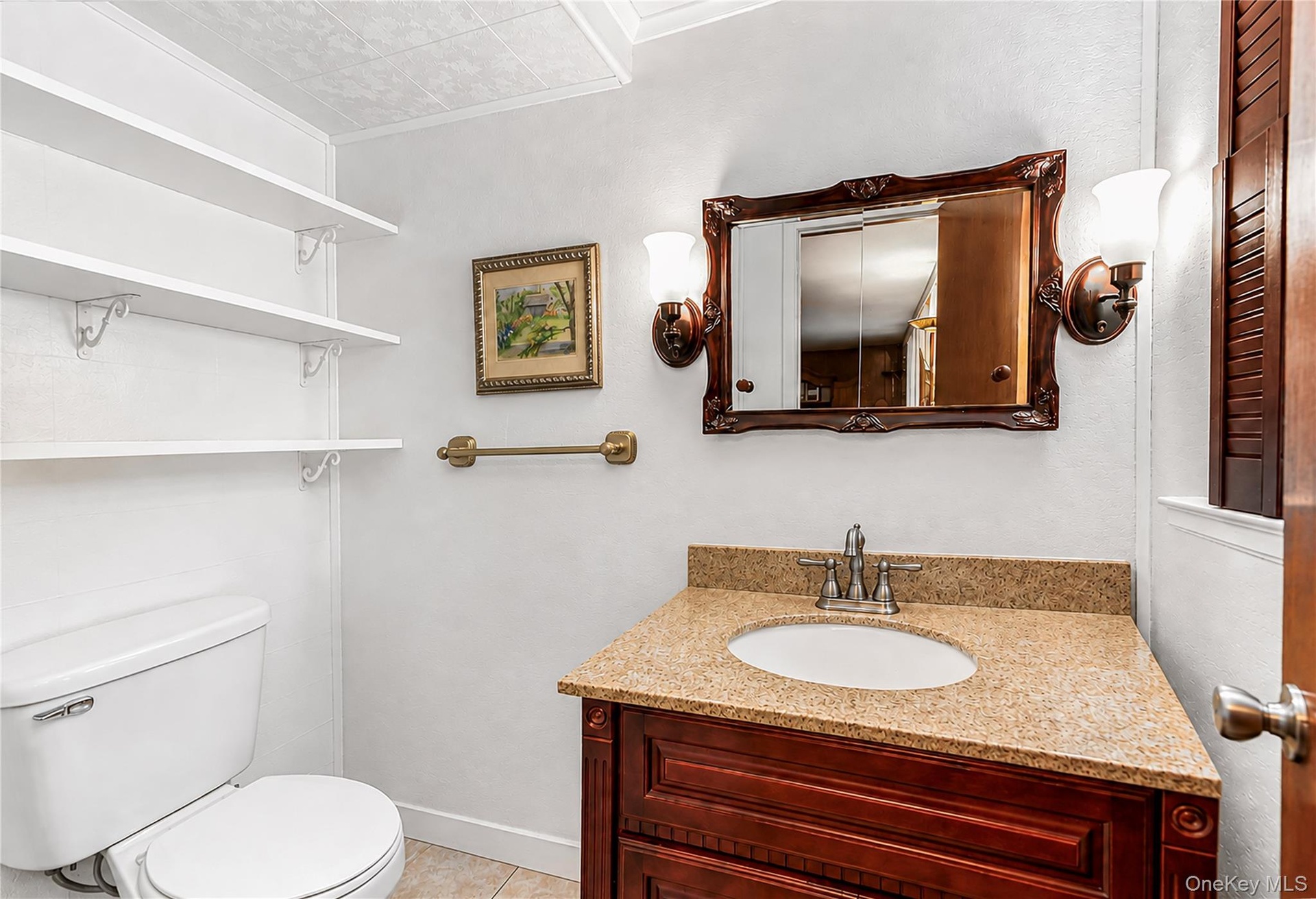 Corner vanity with a light-toned countertop and a decorative wood-framed mirror