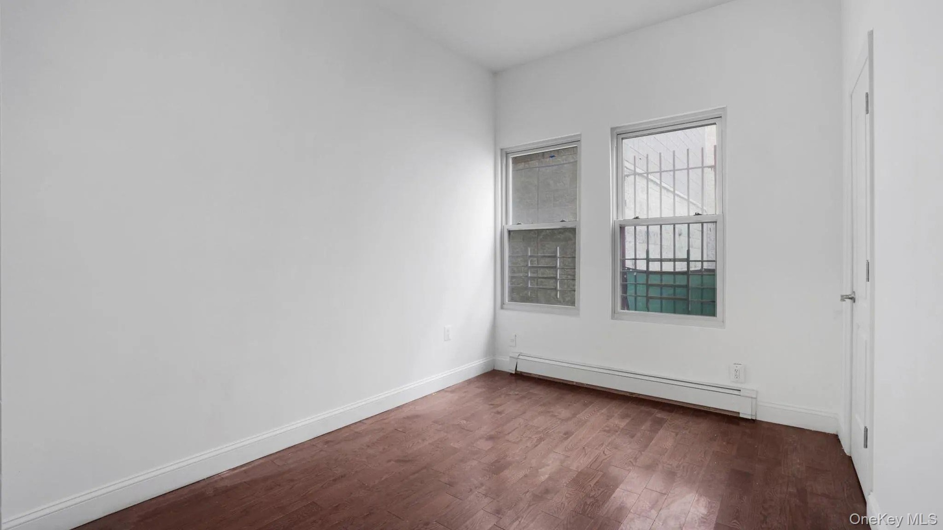 Empty room with a baseboard radiator and dark hardwood / wood-style floors