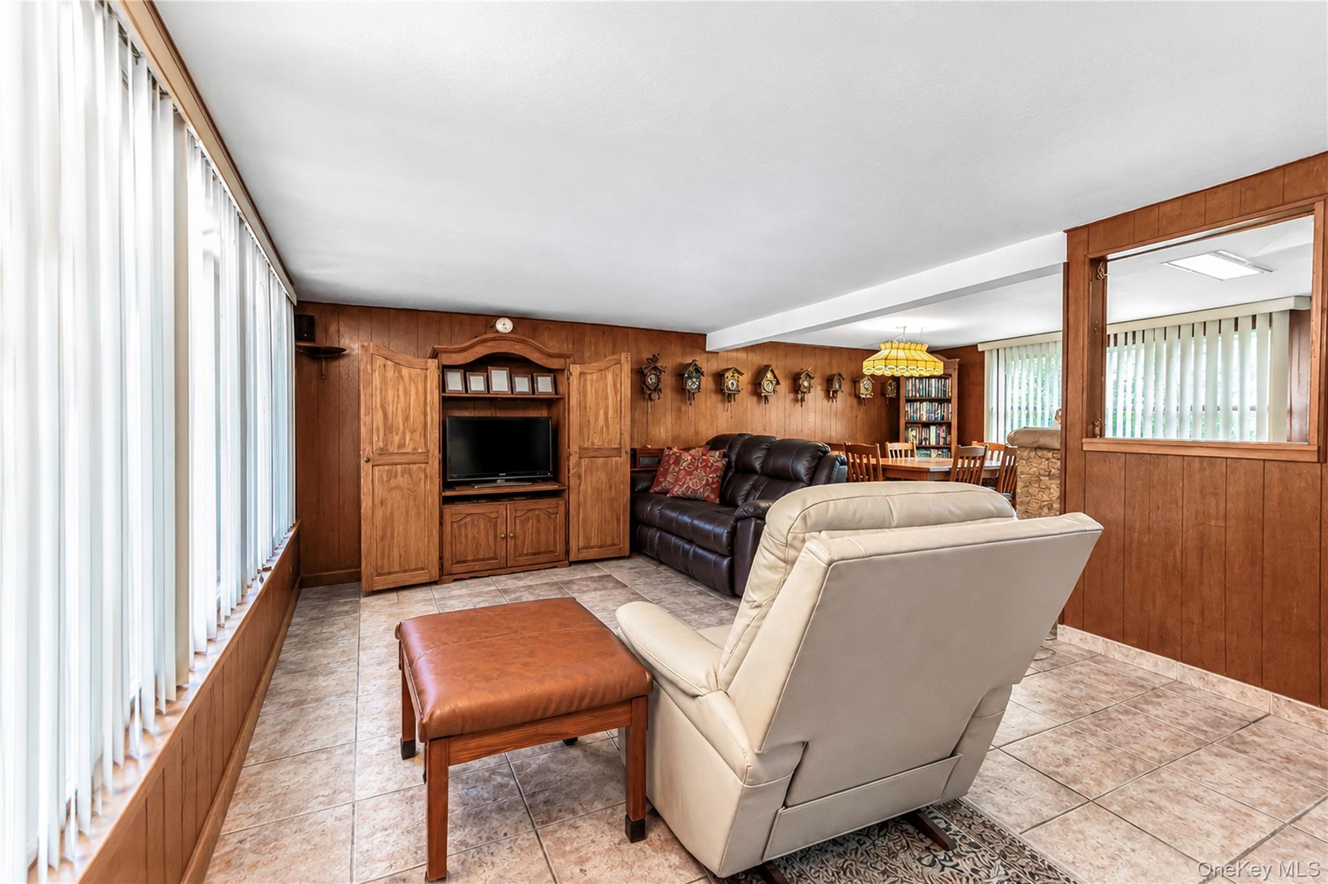 Tiled flooring, wood paneling, built-in media cabinetry, and a pass-through opening