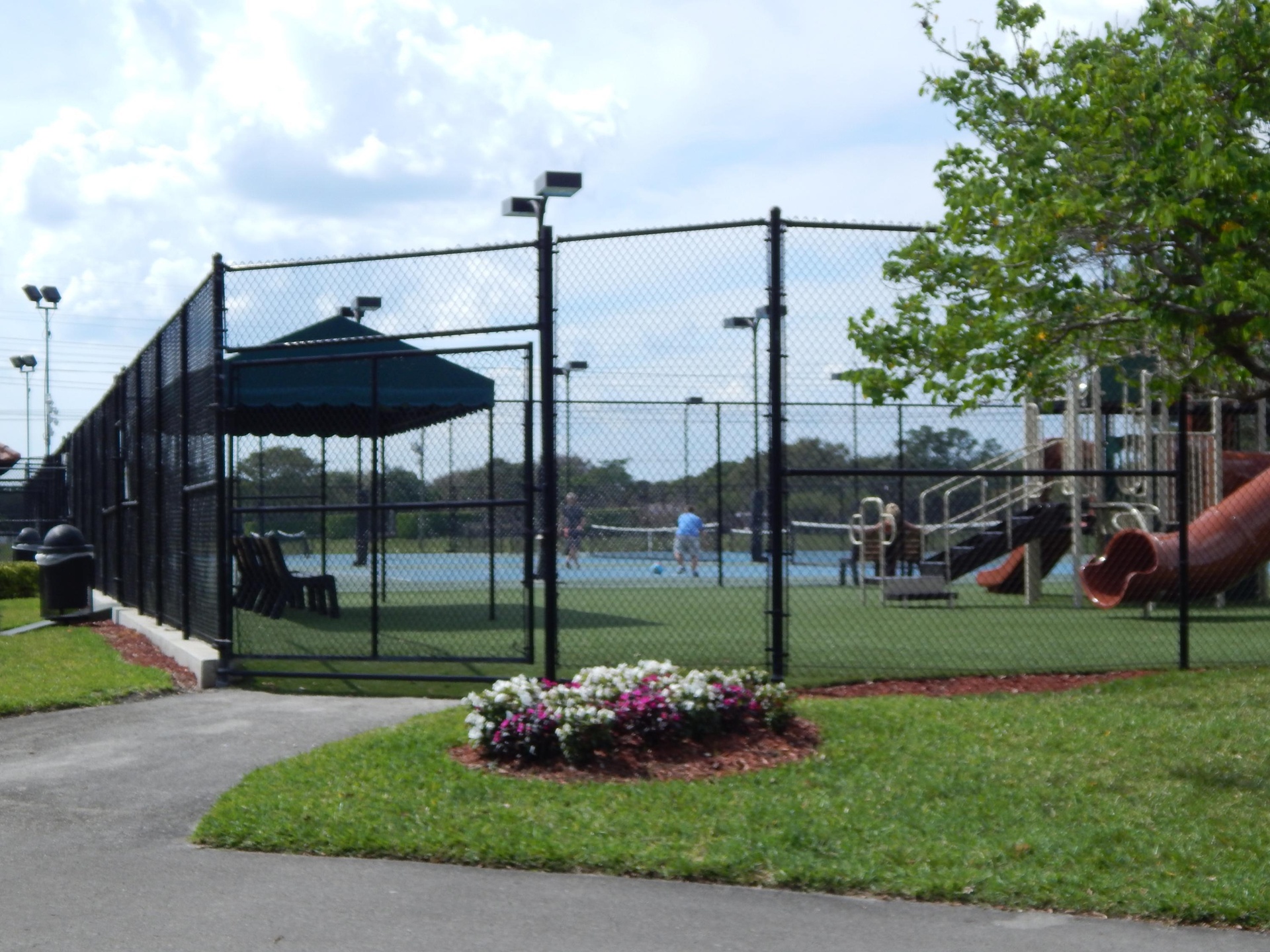 Tennis courts with perimeter fencing and overhead lighting