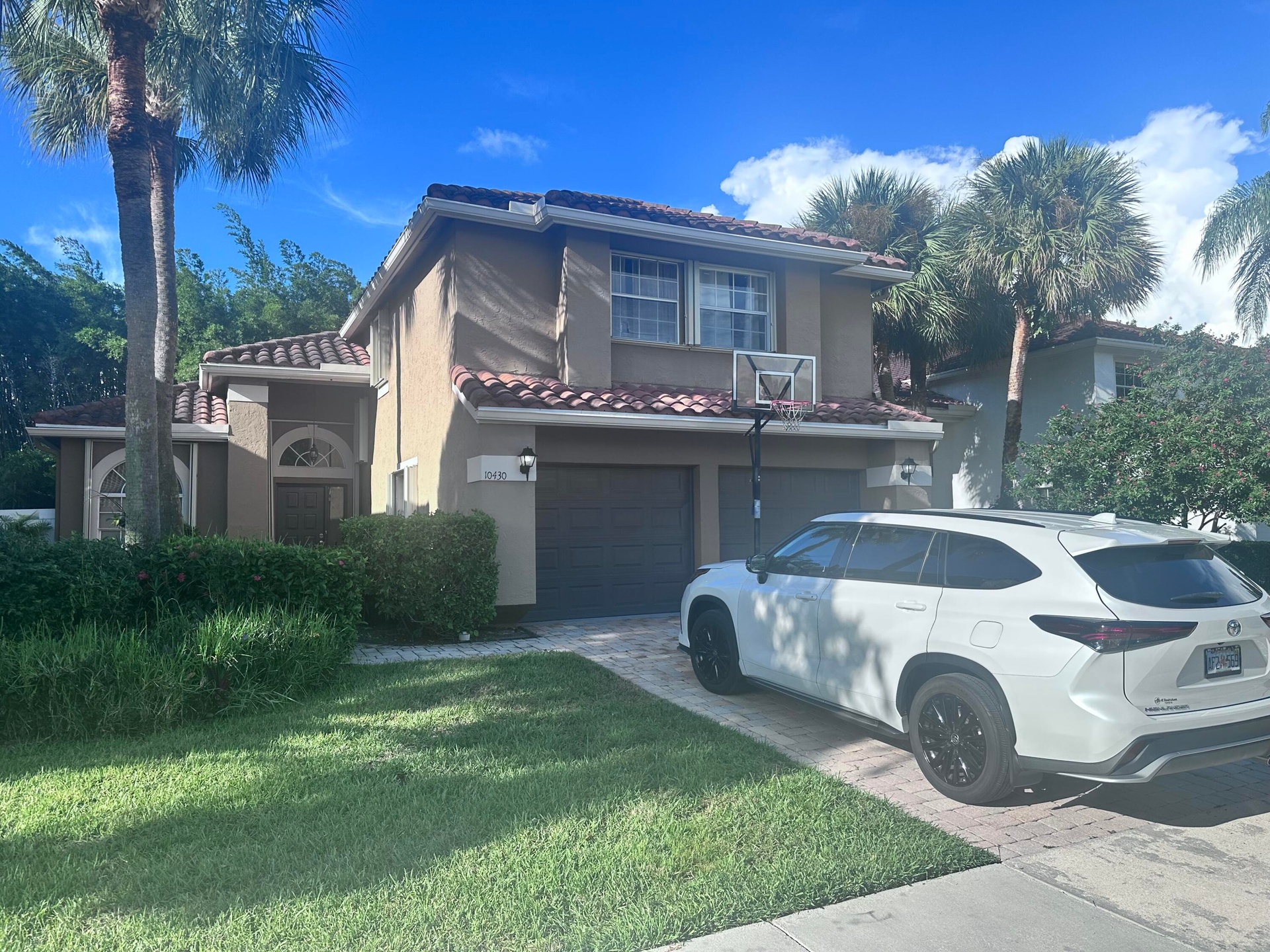 Terracotta-style roof, stucco exterior, arched entry, mature landscaping, and an attached two-car garage