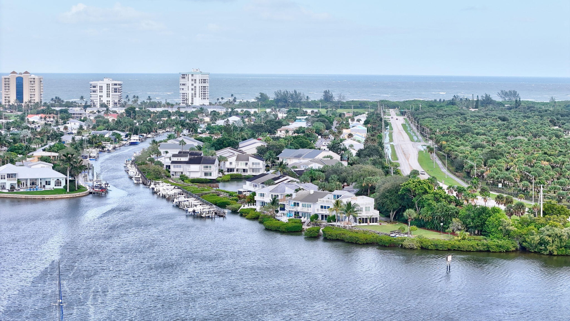 Coastal community with waterway access, lush landscaping, and distant ocean presence