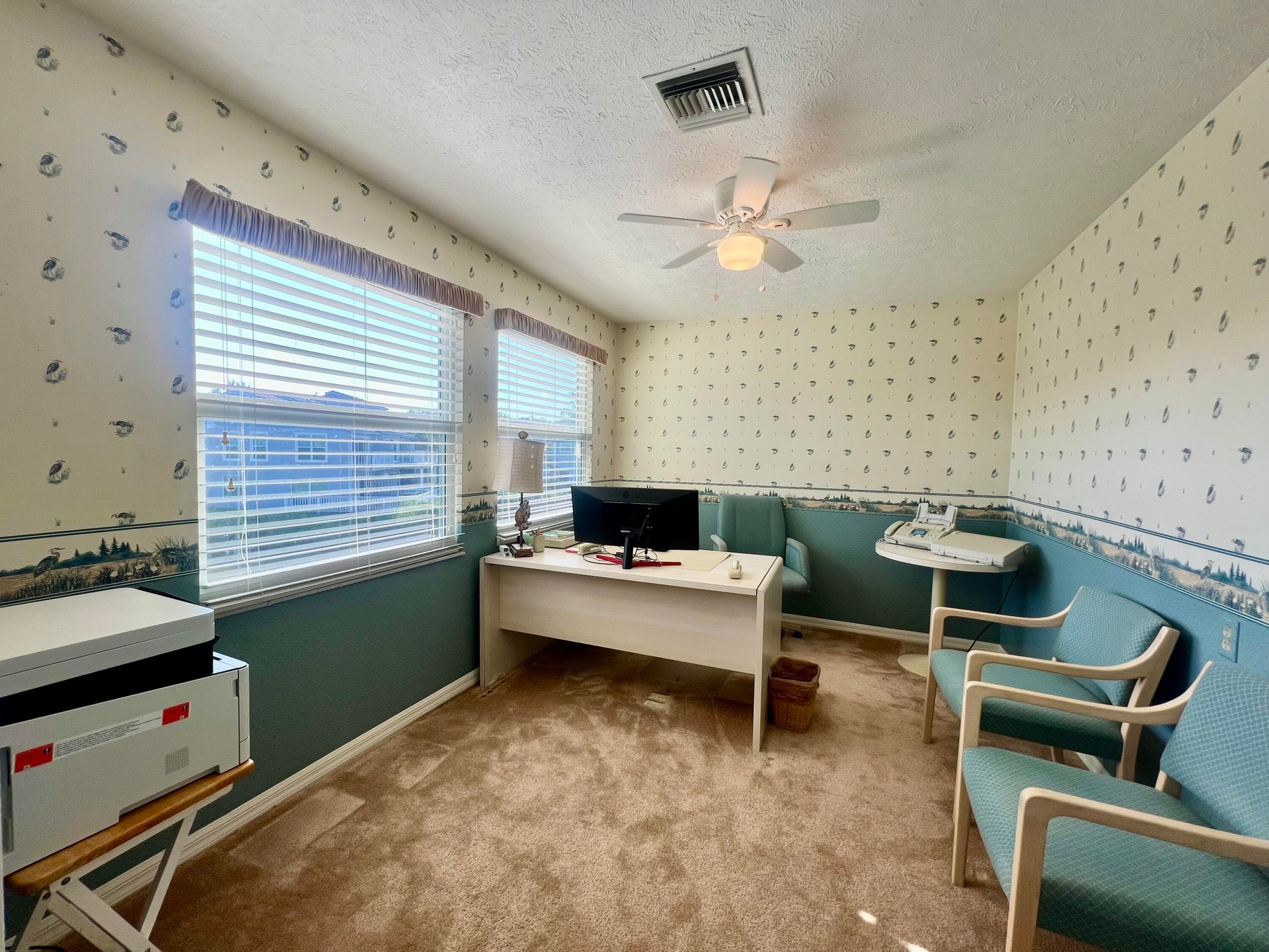 Textured wall covering with patterned accents, dual windows featuring horizontal blinds, ceiling fan with integrated lighting, and plush carpet floori