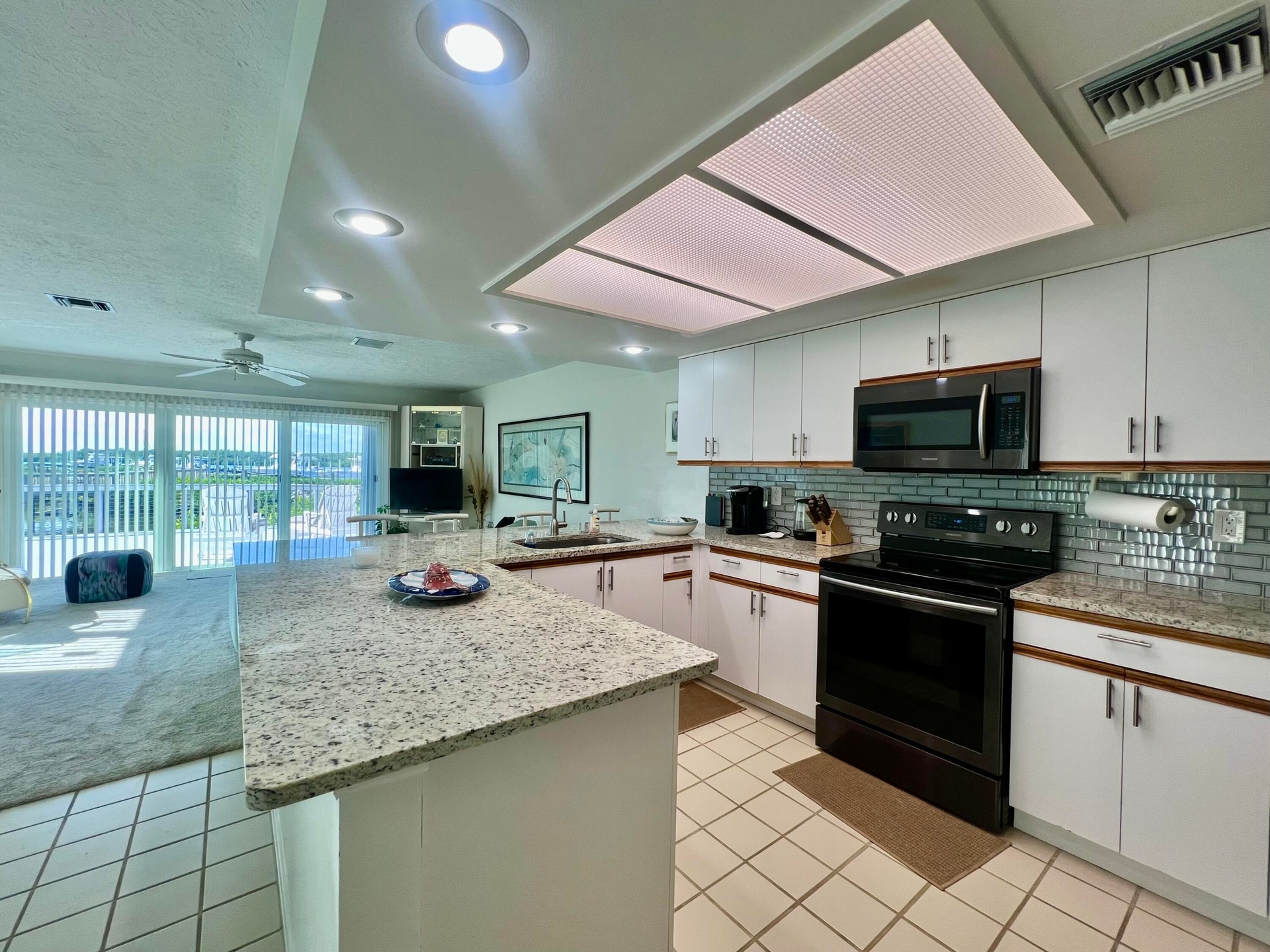 Kitchen featuring white cabinetry with brushed nickel hardware, light-colored granite countertops, a tiled backsplash, and recessed lighting