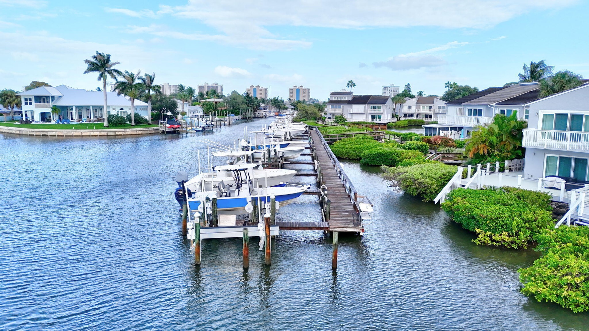 Waterfront property featuring a private boat dock, lush landscaping, multiple balconies, and a canal setting