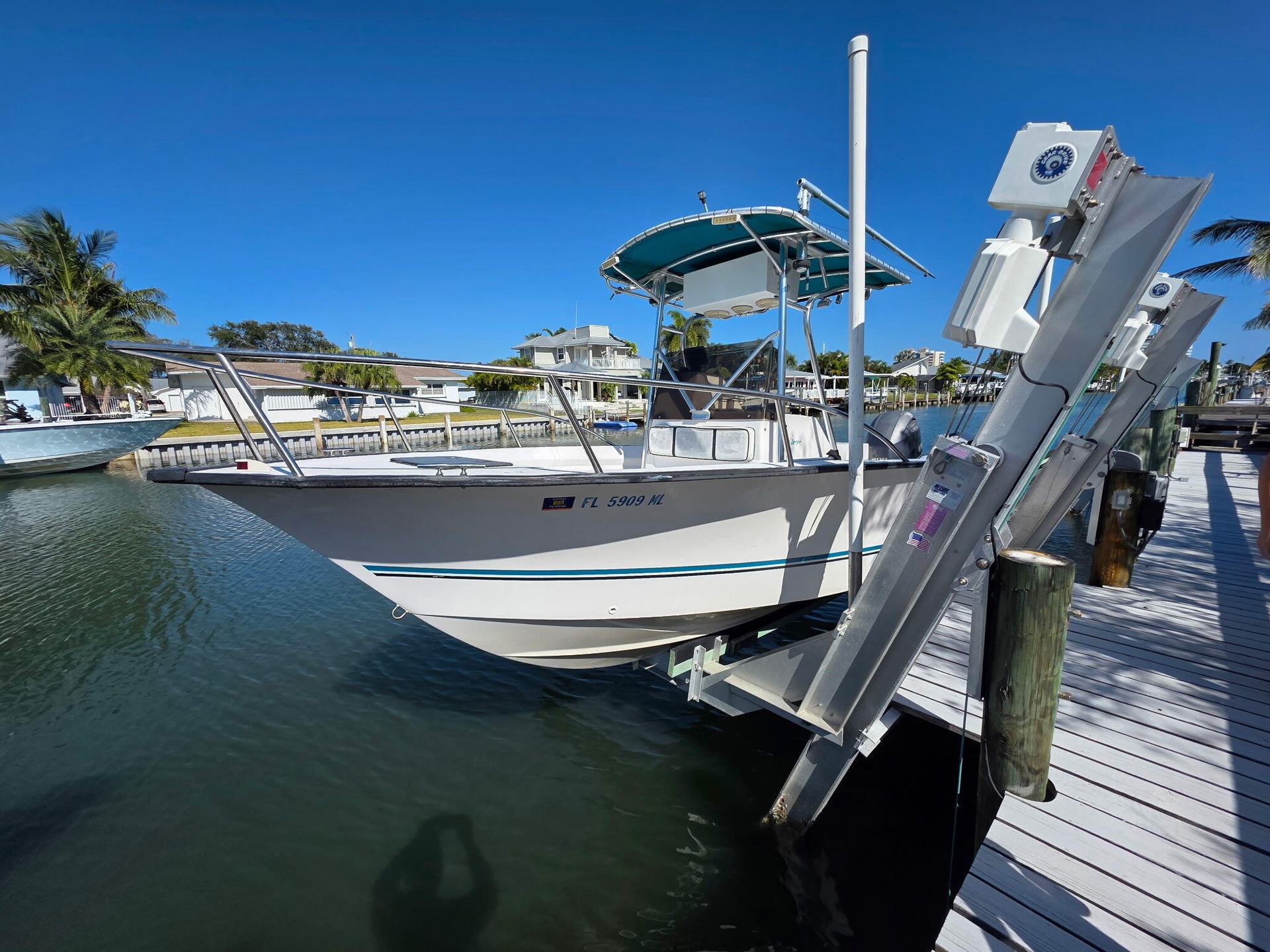 Waterfront access featuring a white boat lift and a wood-plank dock