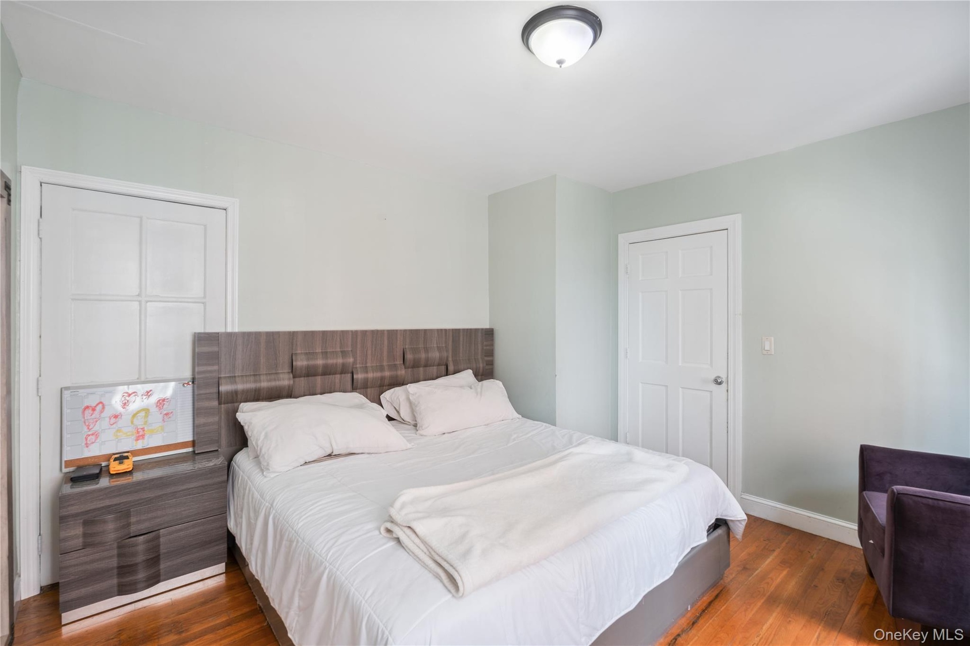 Hardwood flooring, light-toned wall paint, ceiling-mounted light fixture, white paneled doors. 1st Floor.