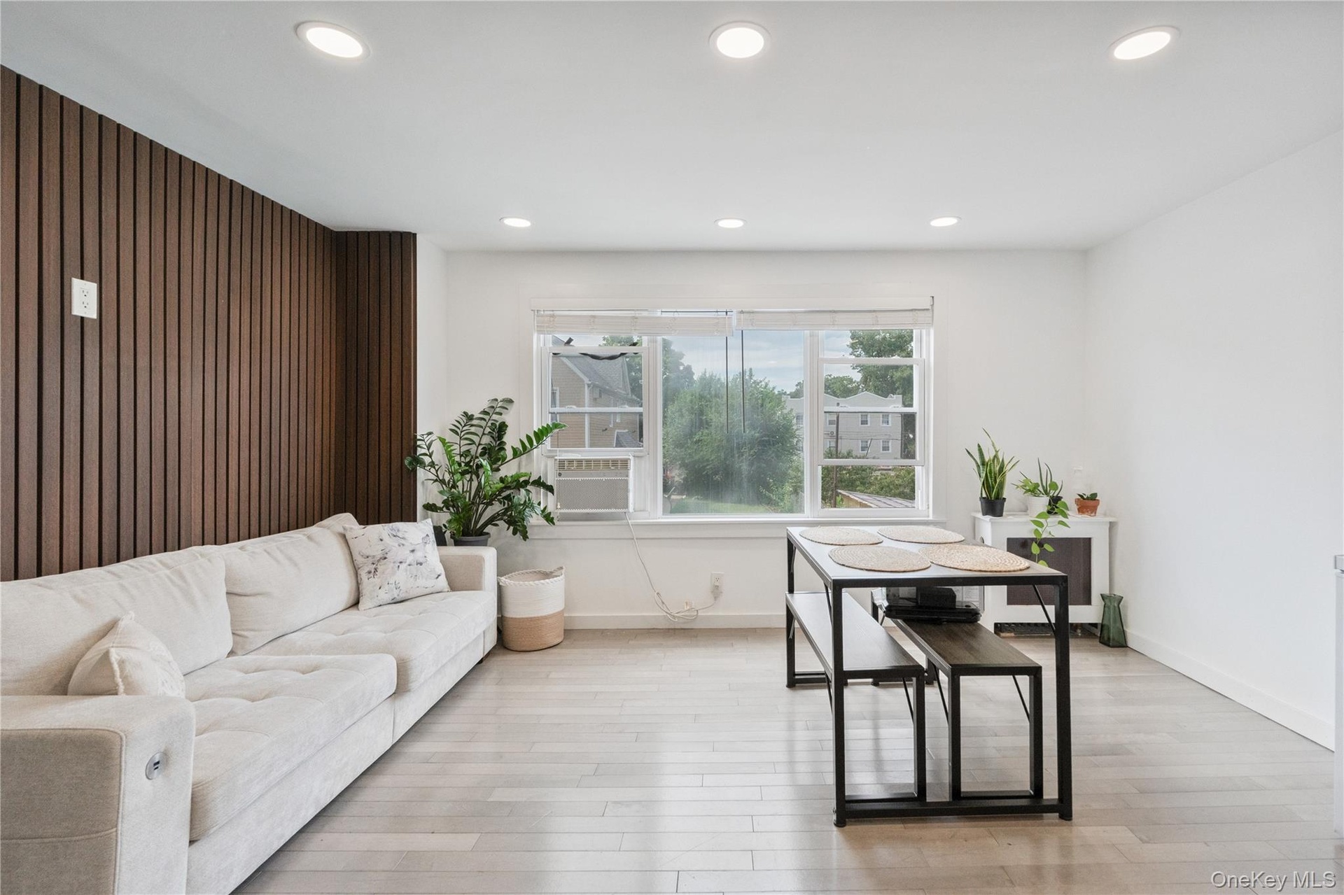 Bright and spacious open-concept living and dining area featuring recessed lighting, modern finishes, and abundant natural light from oversized window