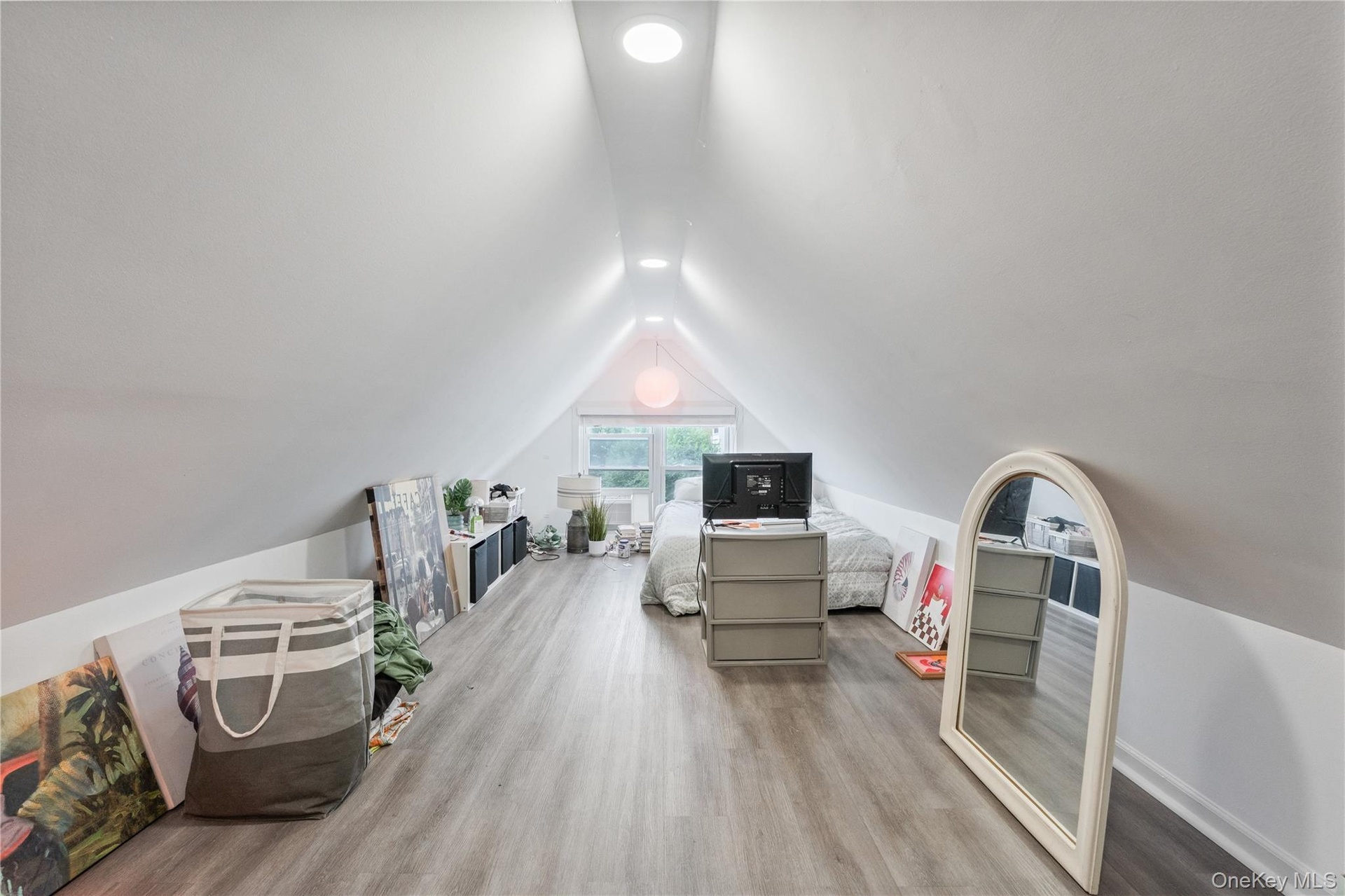 Spacious upper-level bedroom featuring dramatic vaulted ceilings, recessed lighting, updated flooring, and natural light. 2nd Floor Unit.