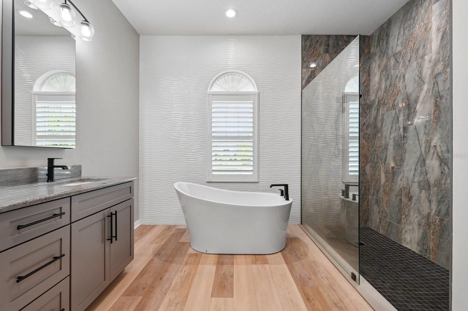 Renovated Primary Bath with Freestanding Tub and Accent Tile Wall