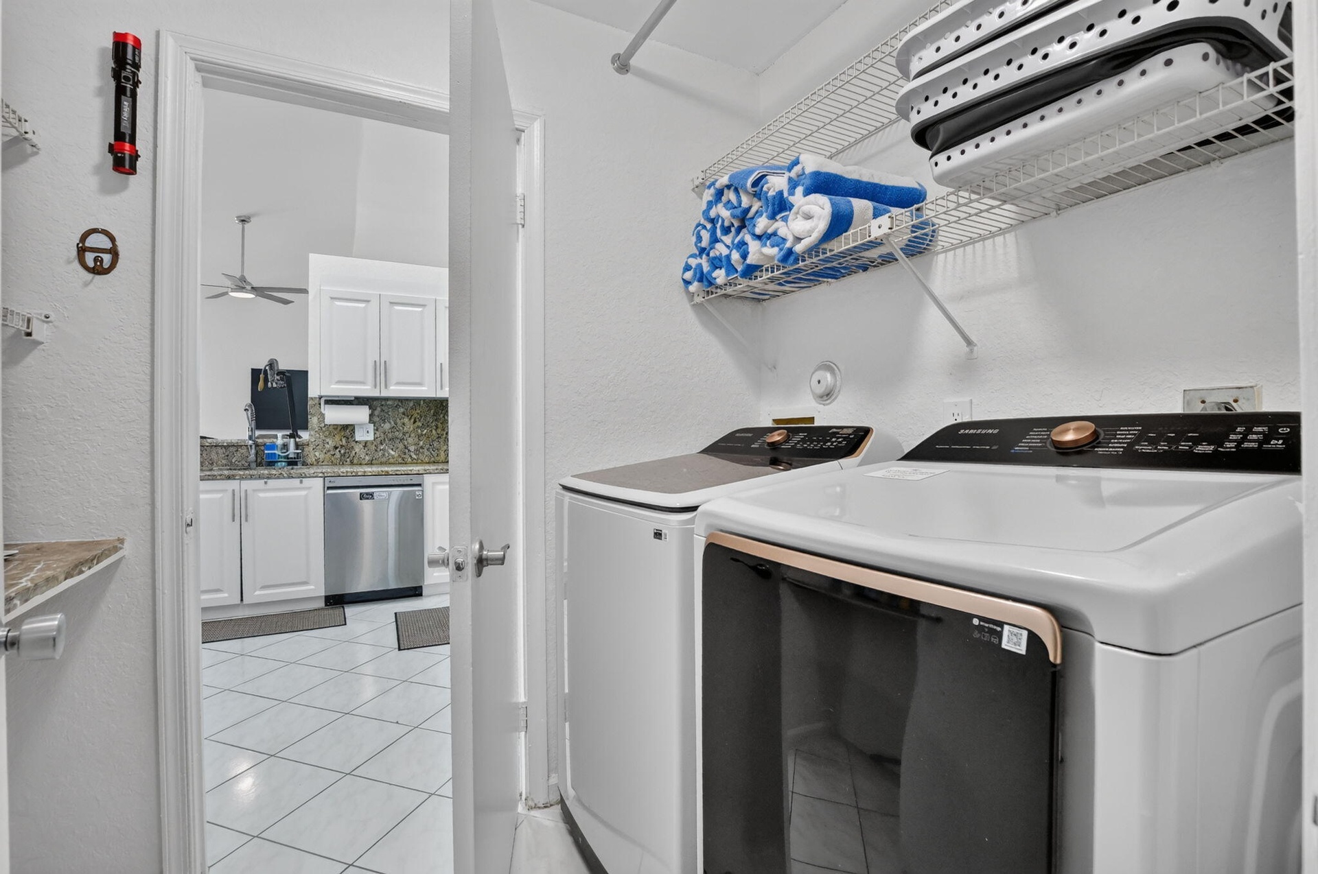 Dedicated laundry area featuring a washer and dryer, wire shelving, and tiled flooring