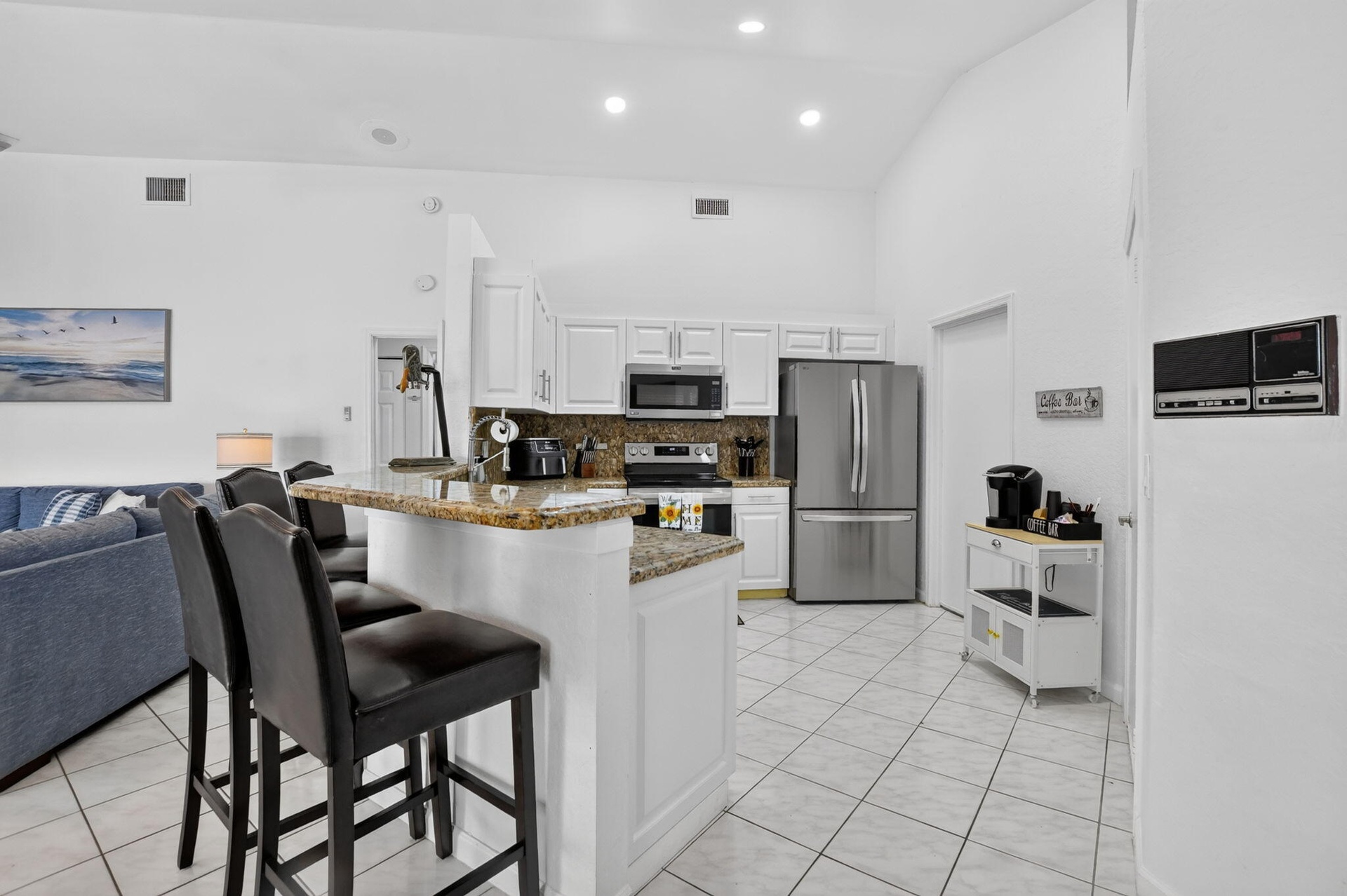 Kitchen featuring white cabinetry, stainless steel appliances, a counter-height breakfast bar, tile flooring, and recessed lighting