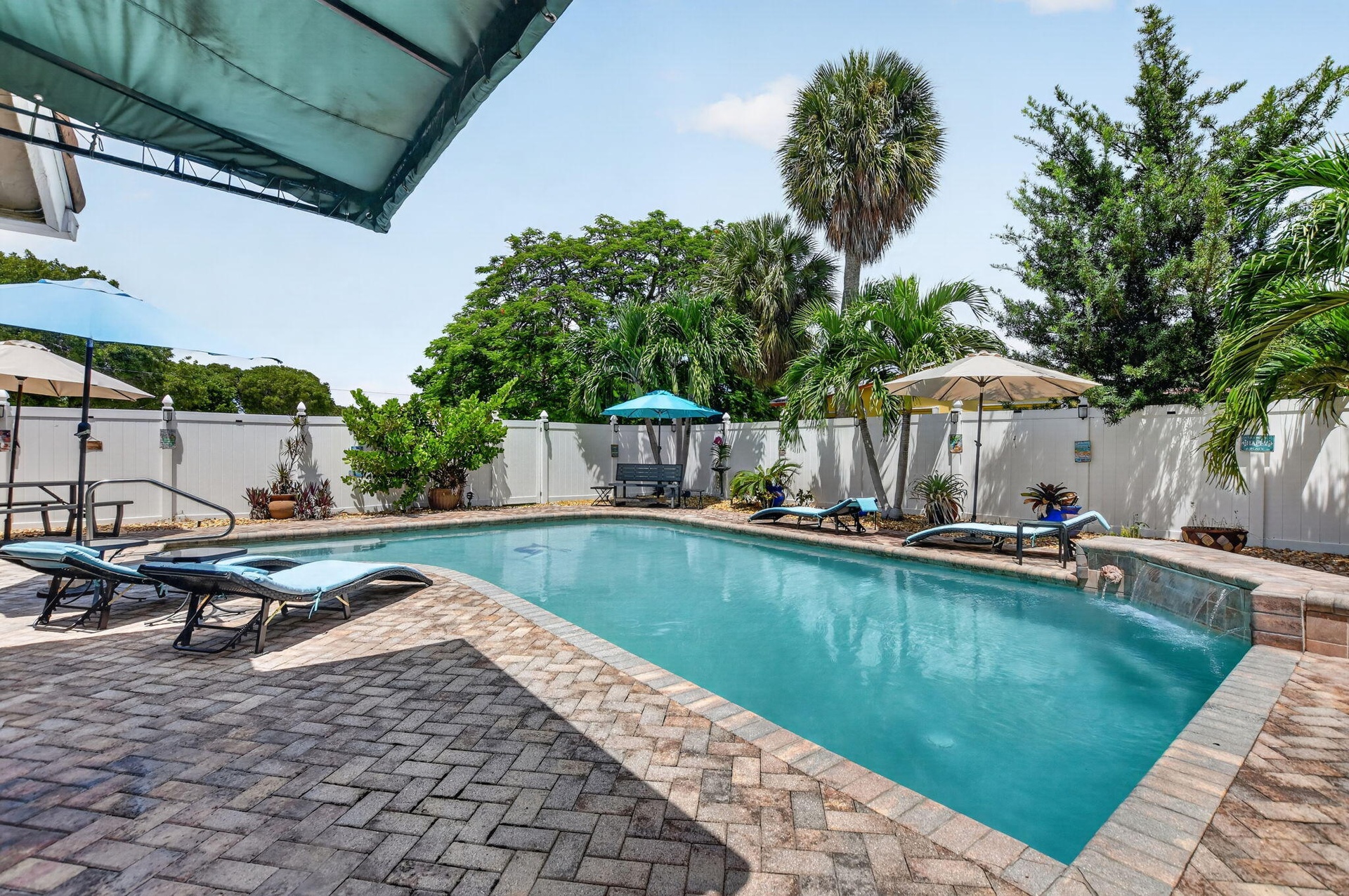 Rectangular swimming pool with brick paver decking and a water feature