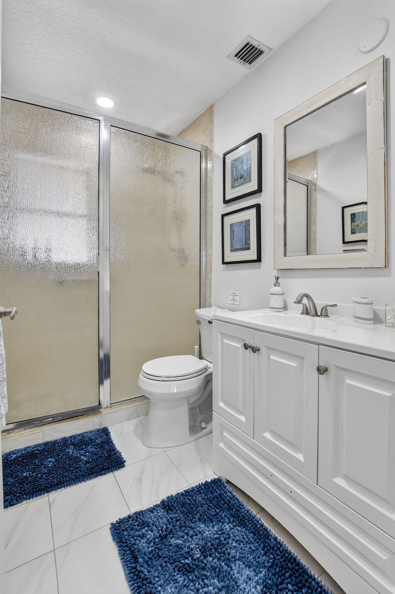White vanity with cabinet storage, a top-set sink, and a framed mirror