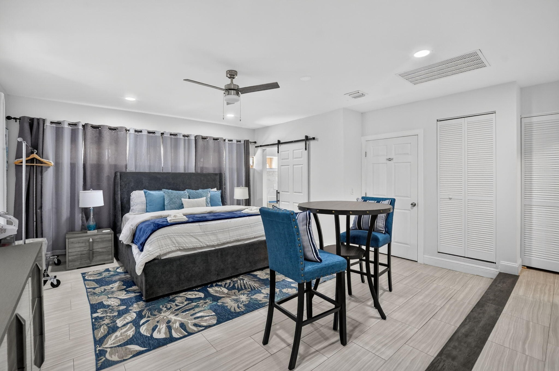 Recessed lighting, ceiling fan with integrated light, light-toned tile flooring, white louvered bifold doors, and a barn door
